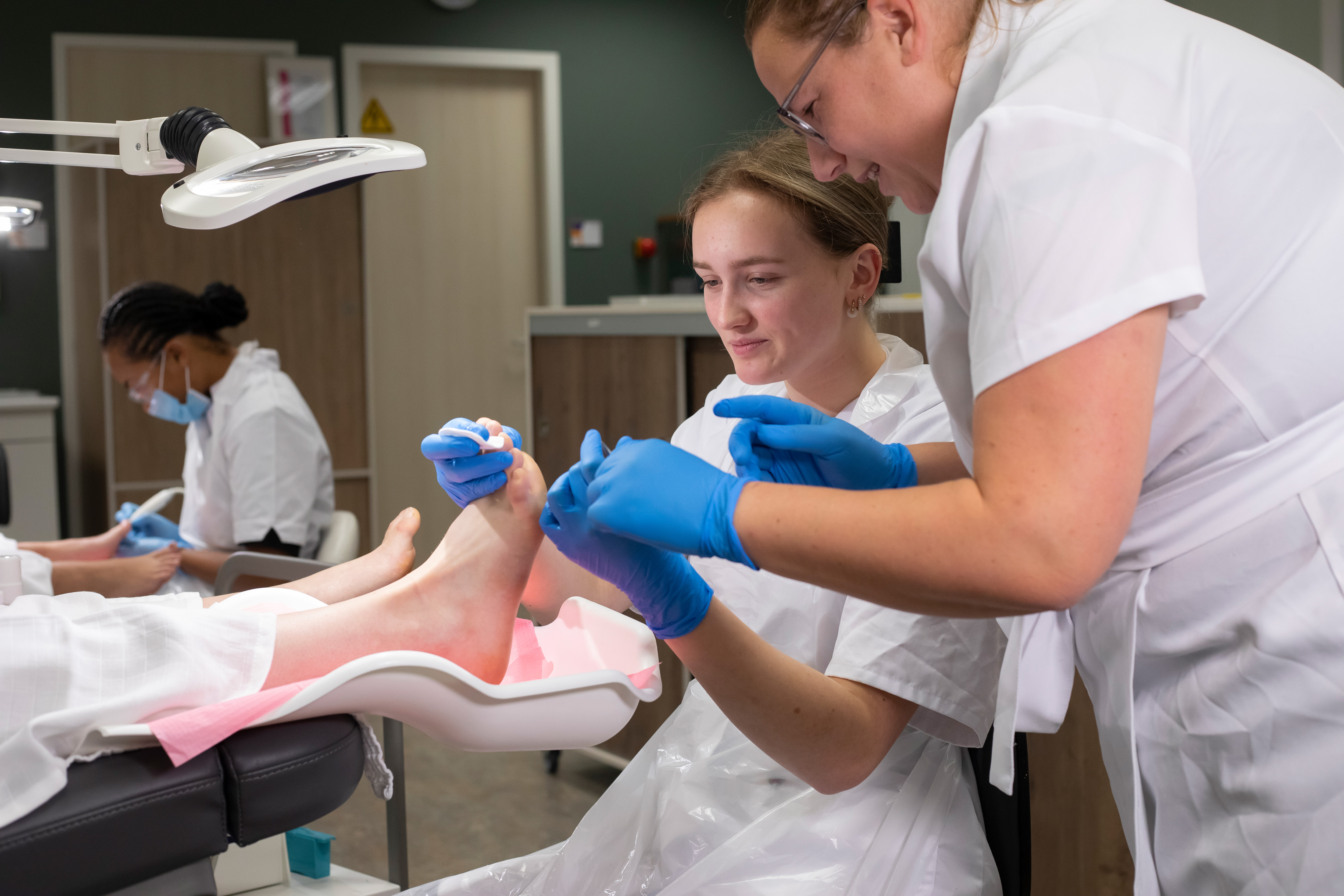 Docent helpt een student met het schoonmaken van iemands voet