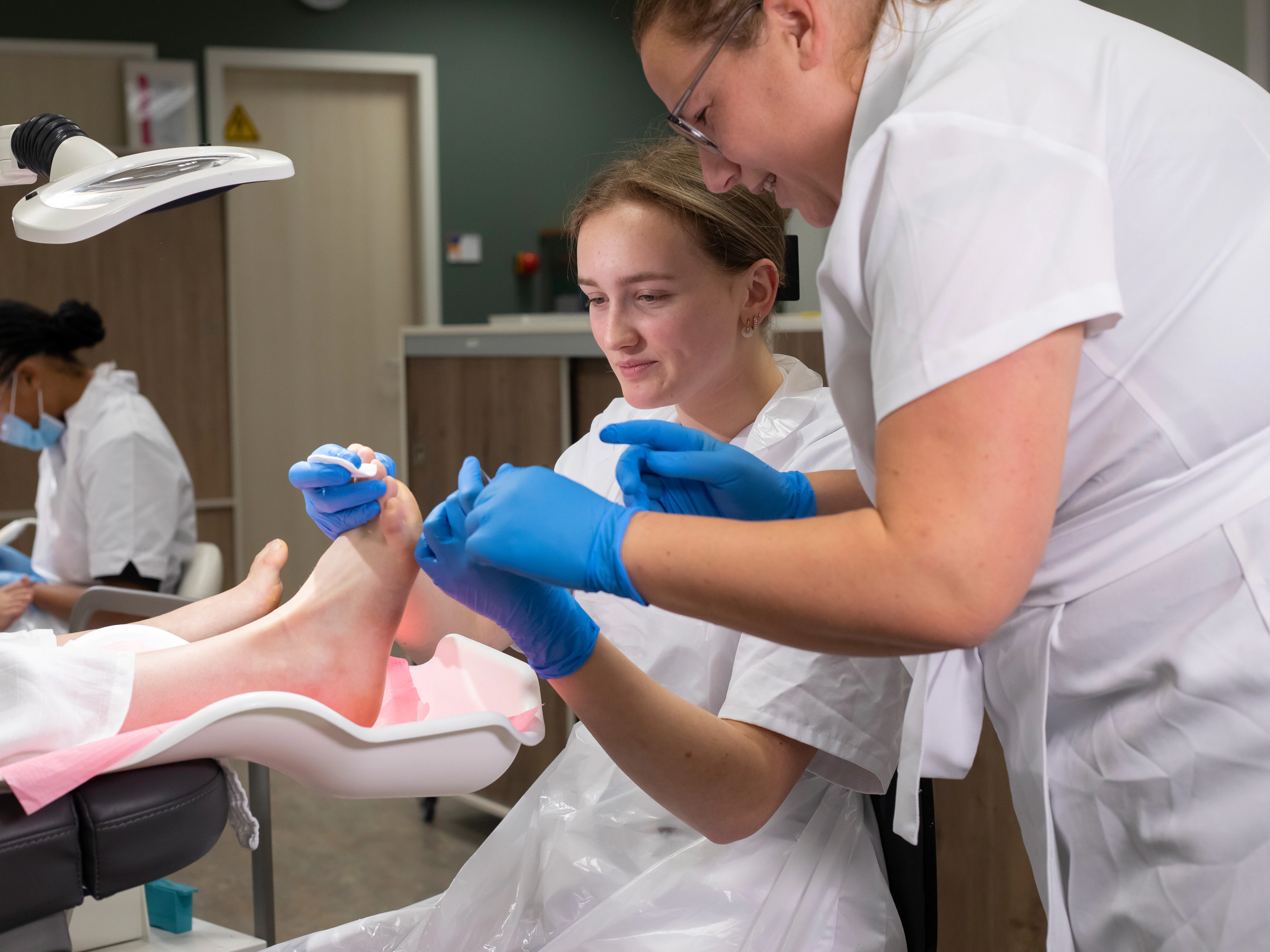 Docent helpt een student met het schoonmaken van iemands voet