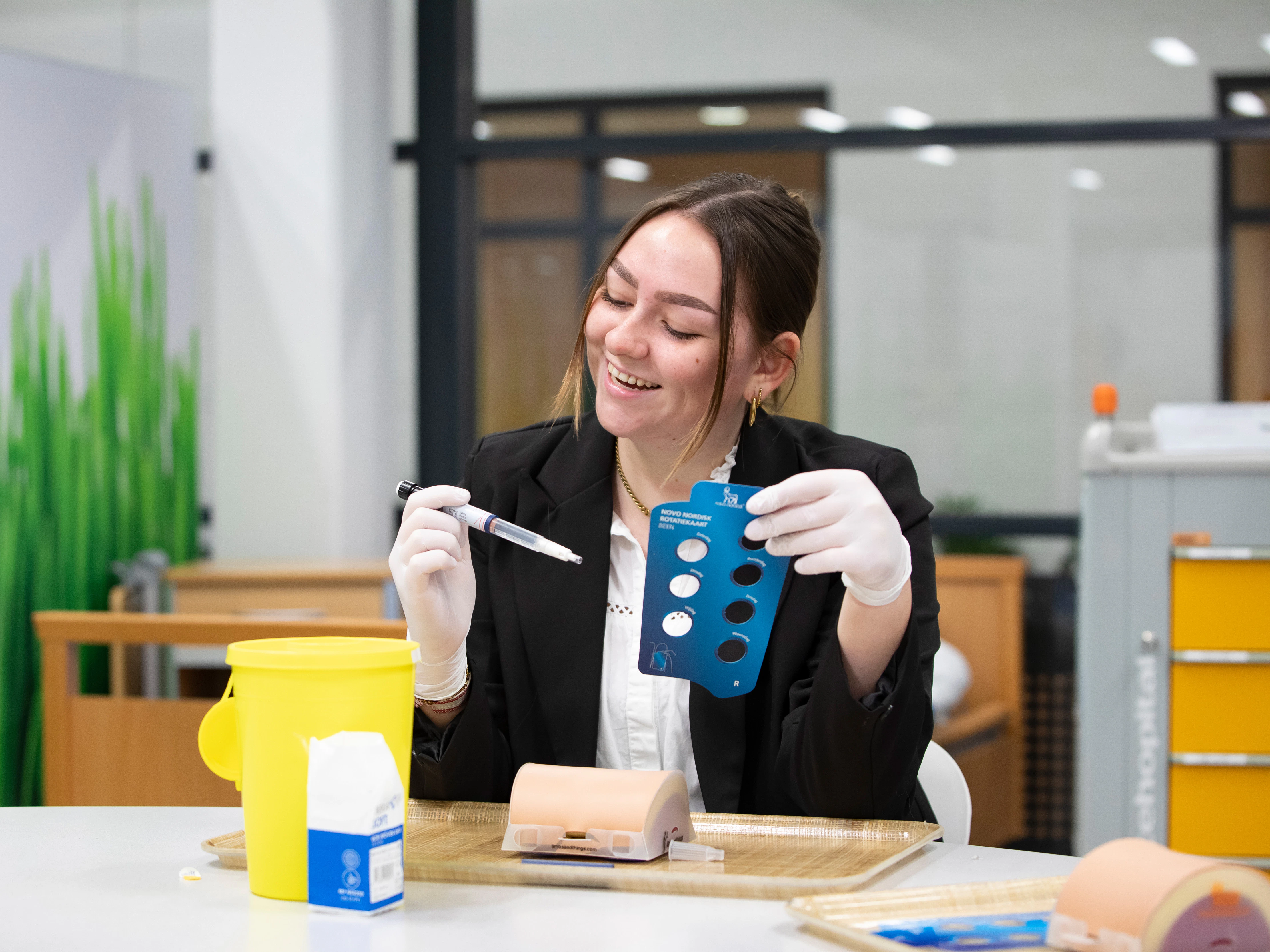 Student heeft een spuit in de hand en zit aan tafel