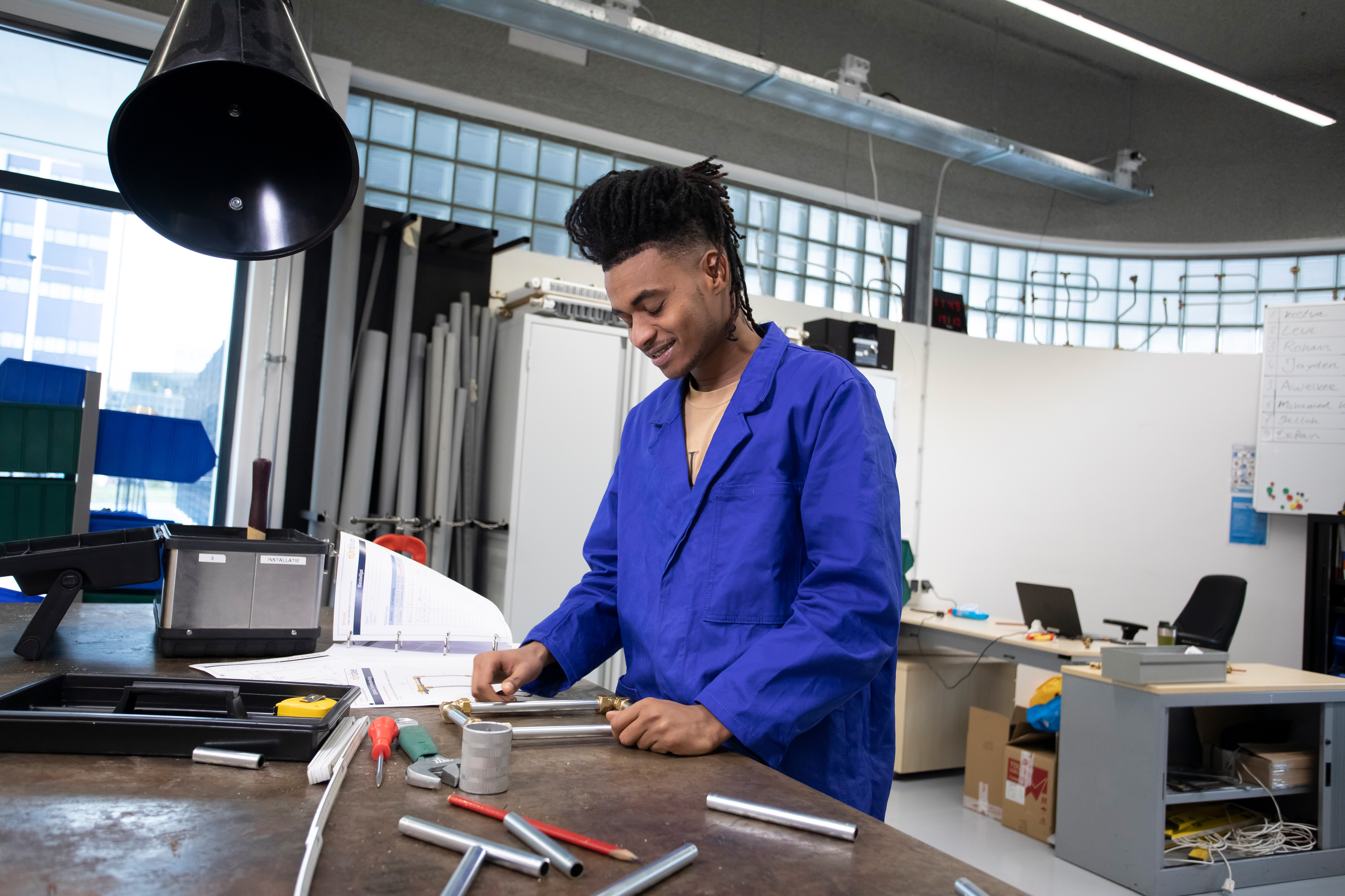 Student is bezig in de werkplaats met buizen