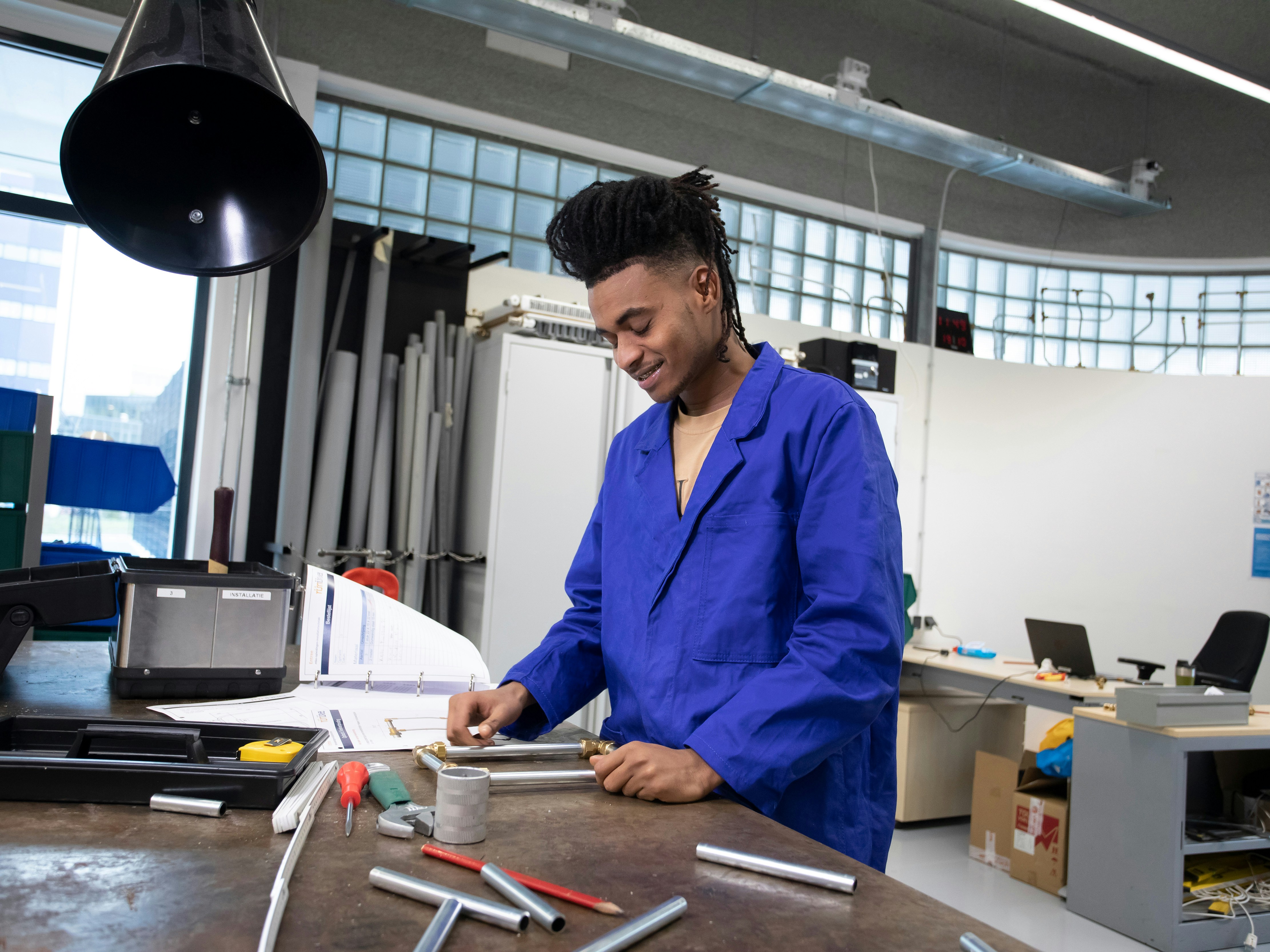 Student is bezig in de werkplaats met buizen