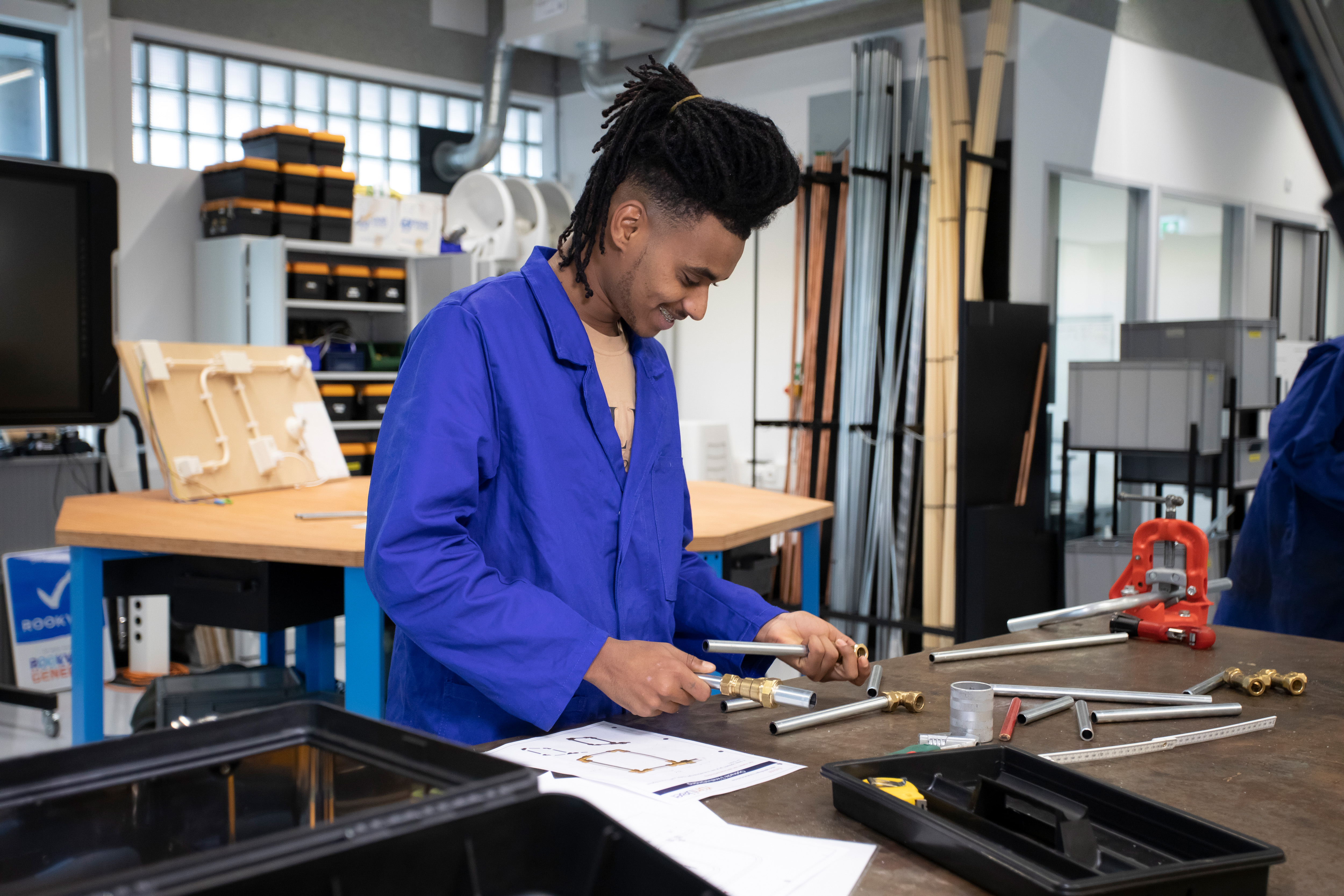 Student is bezig in de werkplaats met buizen