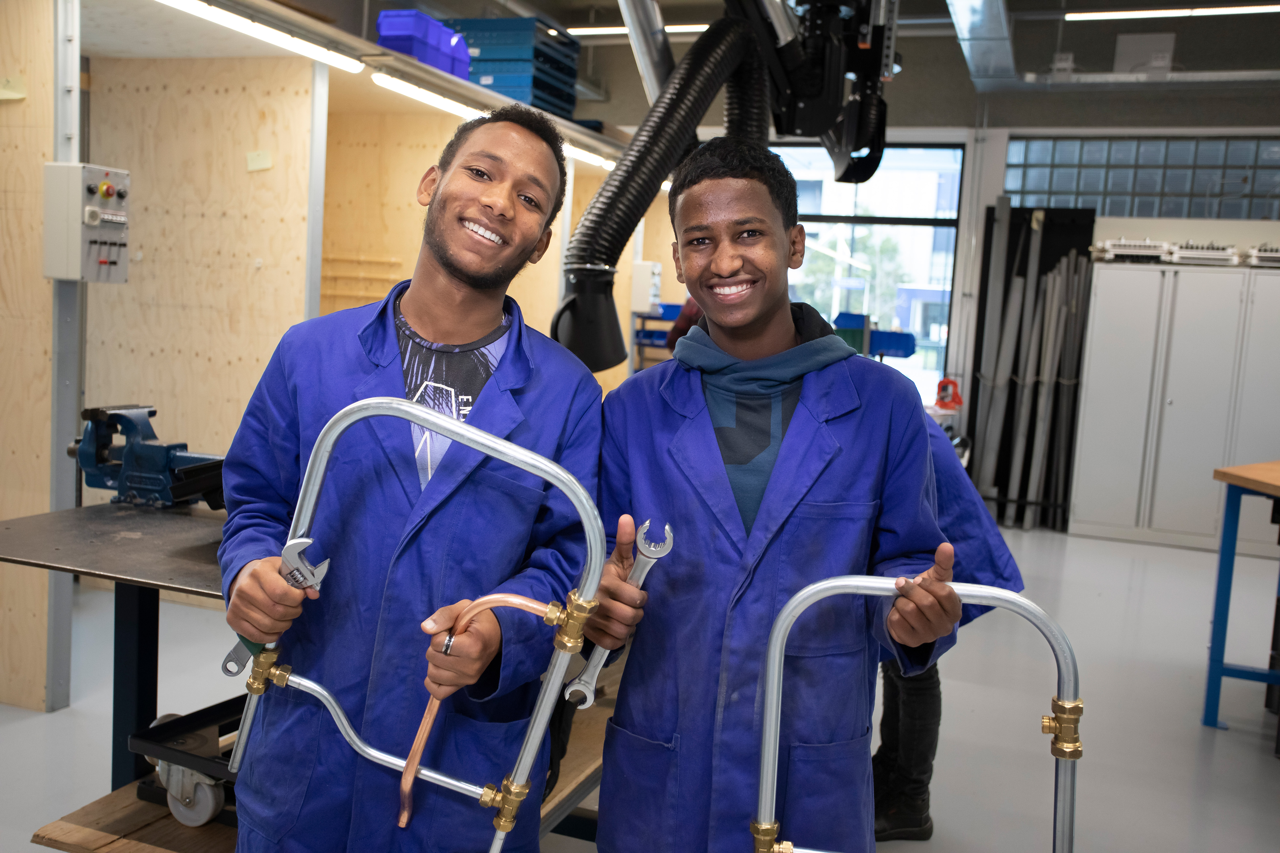 Twee studenten in blauwe werkkleding poseren voor de camera