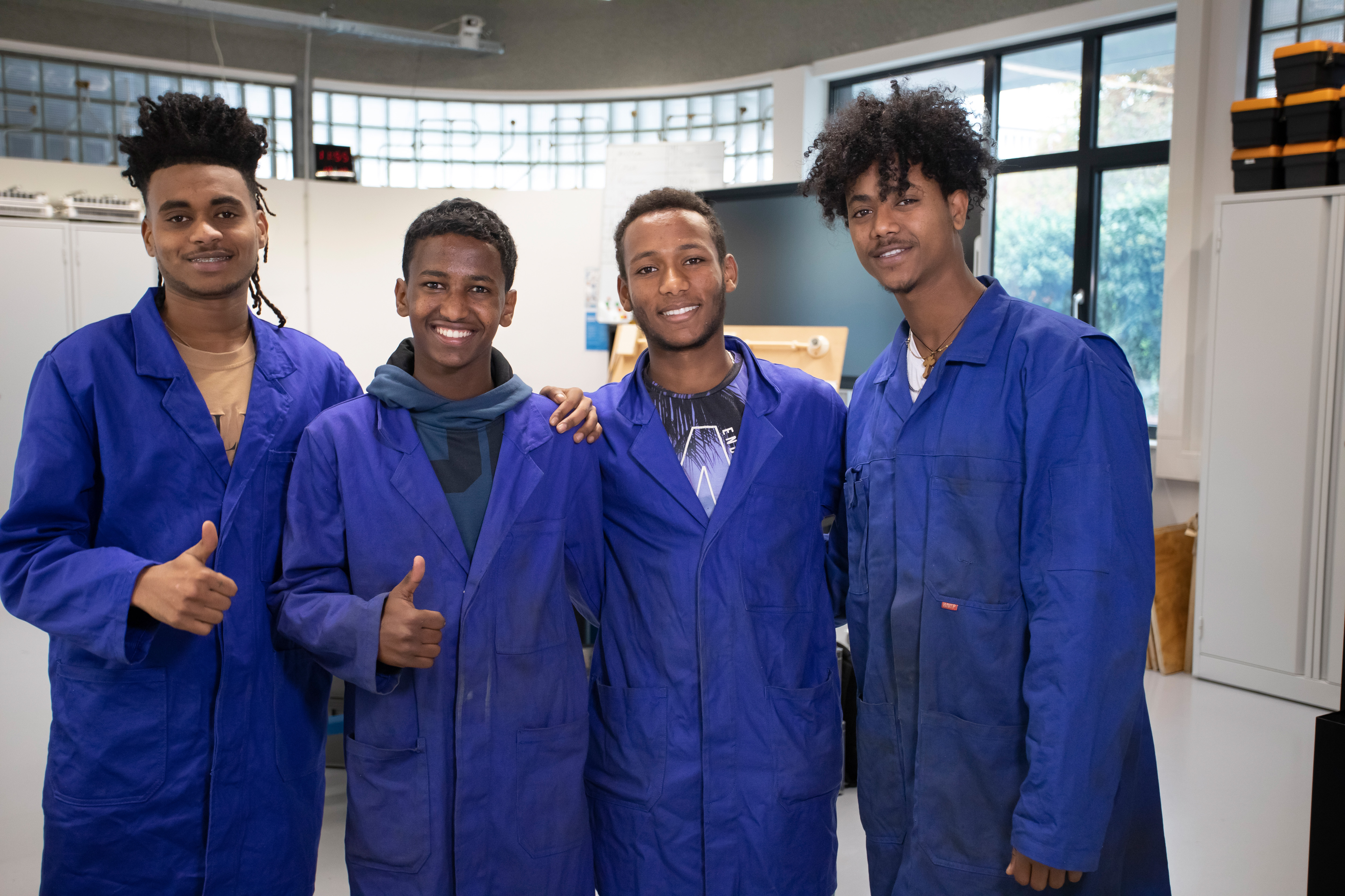 Studenten in blauwe werkkleding poseren voor de camera
