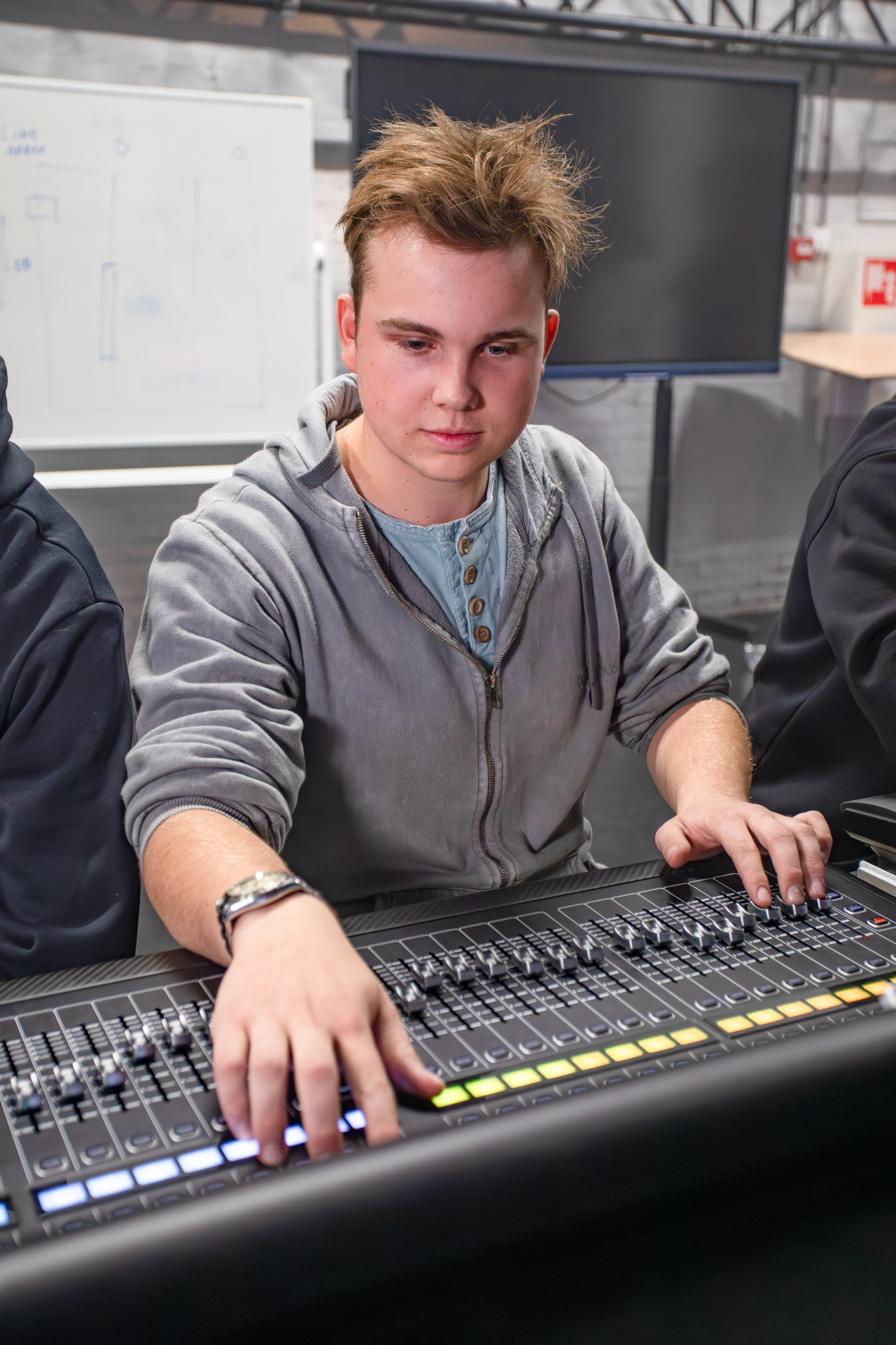 twee studenten kijken naar een laptopscherm. Er ligt ook een koptelefoon op tafel