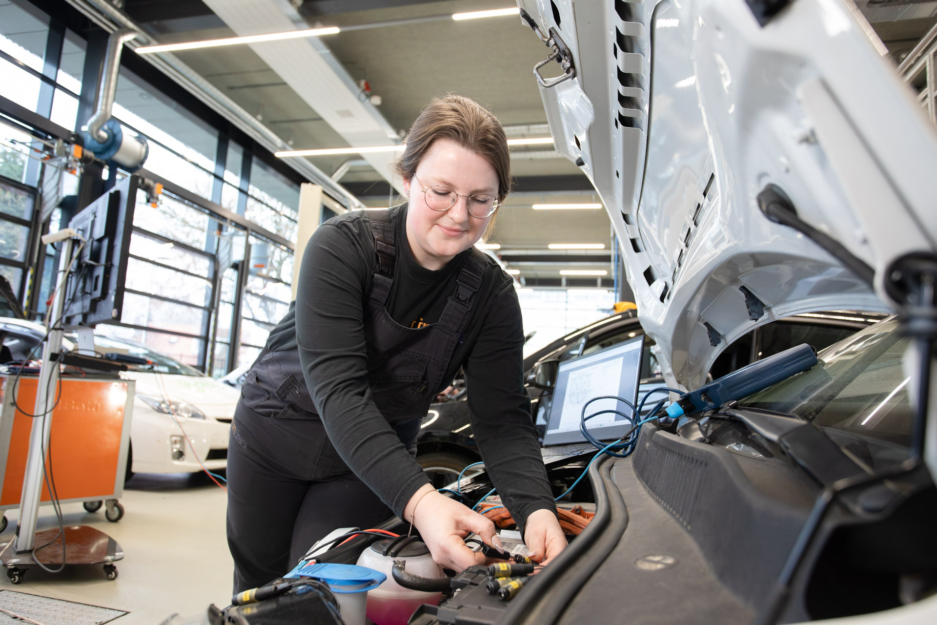 Meisje sluit een kabel aan onder de motorkap van een auto