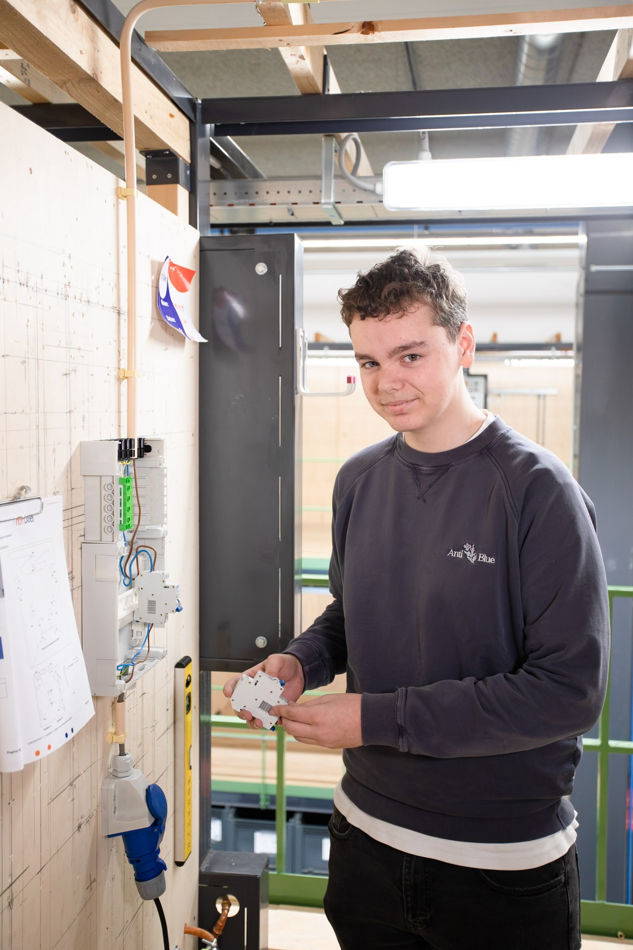 Jongen kijk in de camera terwijl hij een component van een groepenkast in de hand houdt