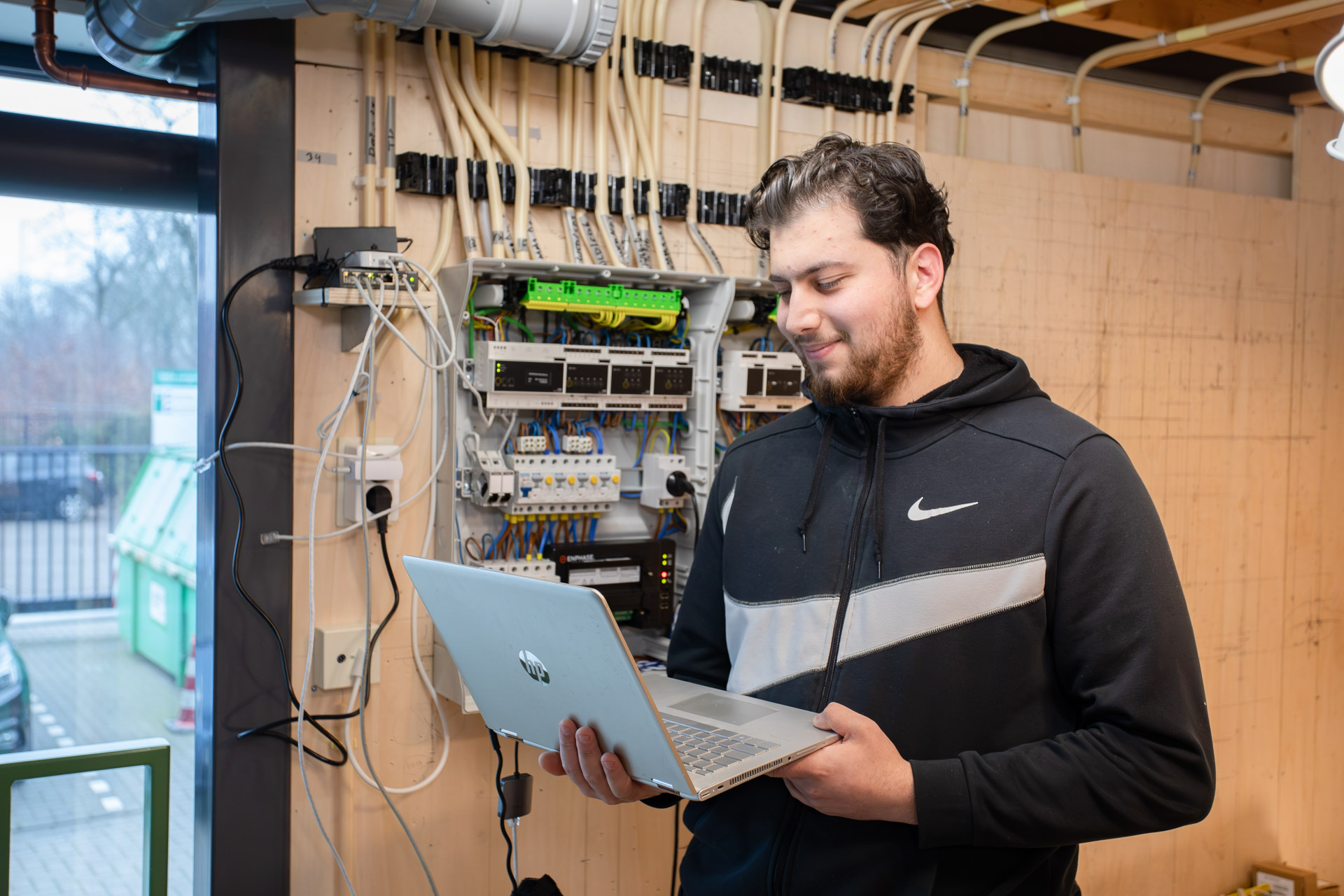 Jongen heeft een laptop in zijn hand terwijl hij voor een groepenkast staat