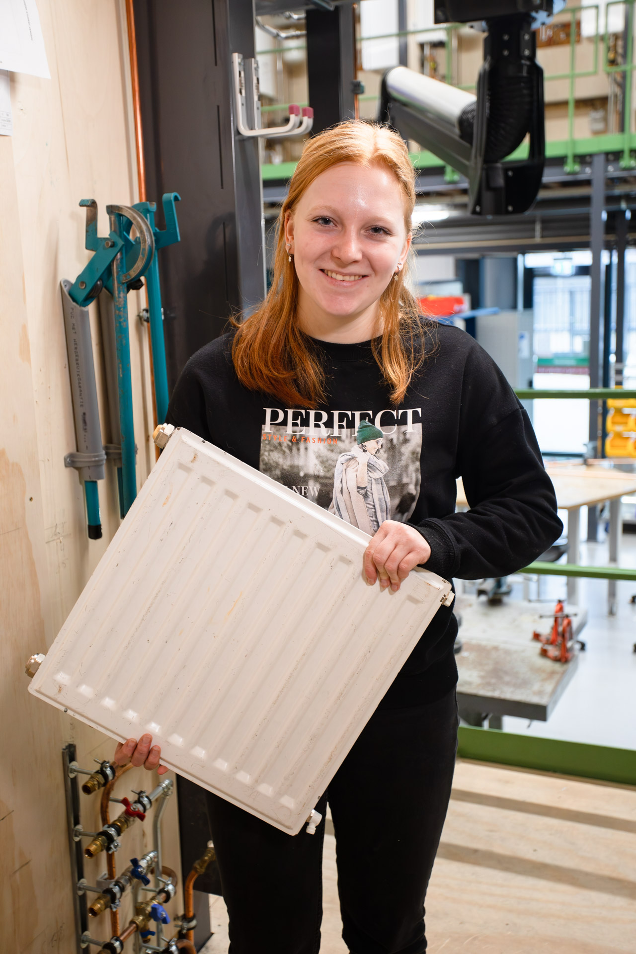 Meisje kijkt in de camera terwijl ze een radiator vasthoudt