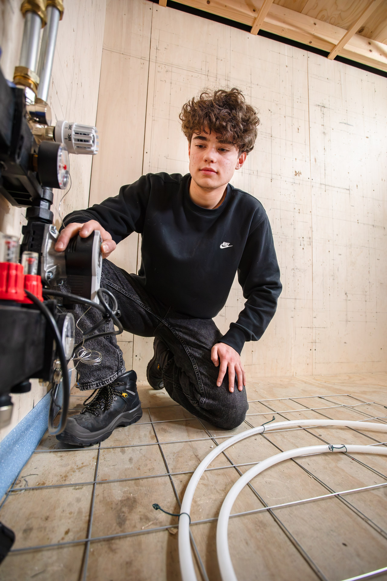 Een jongen kijkt naar het systeem van vloerverwarming