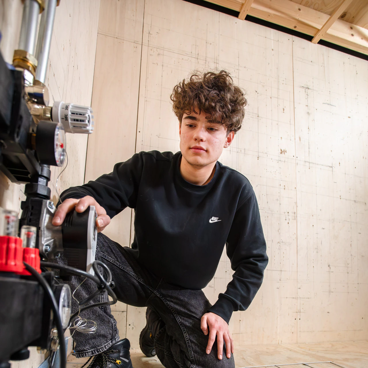 Een jongen kijkt naar het systeem van vloerverwarming