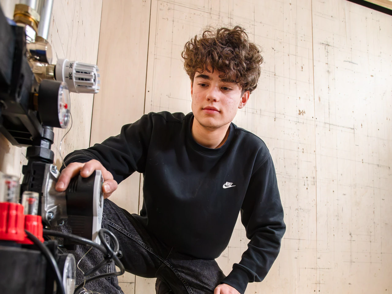 Een jongen kijkt naar het systeem van vloerverwarming