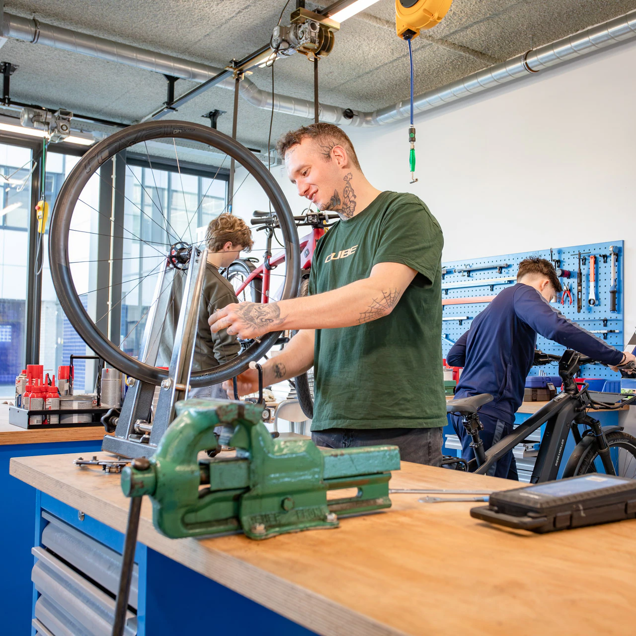 Een jongen in een fietsenwerkplaats een band aan het spaken is.