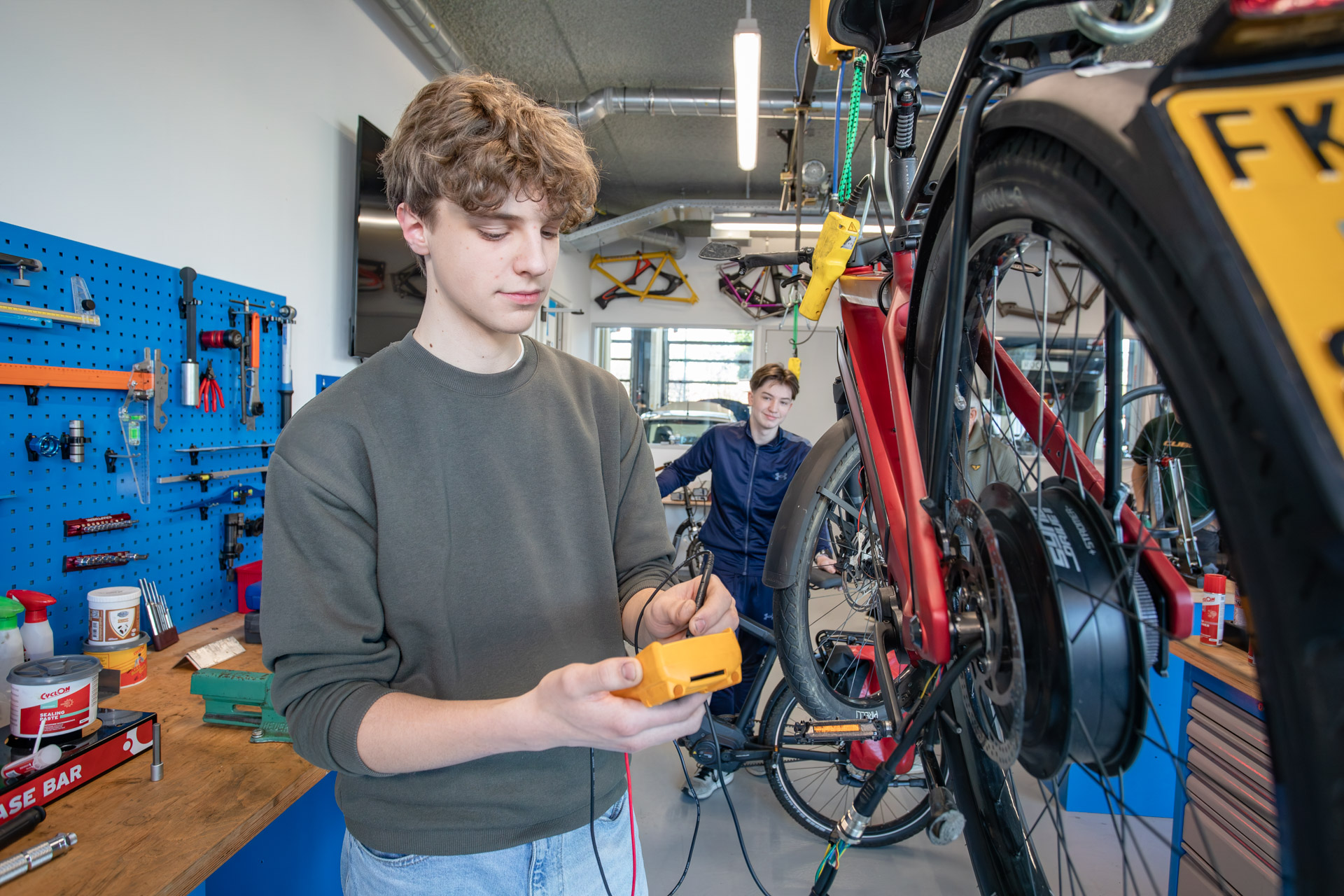 Een jongen in een fietsenwerkplaats die de bandenspanning van de fiets controleert.