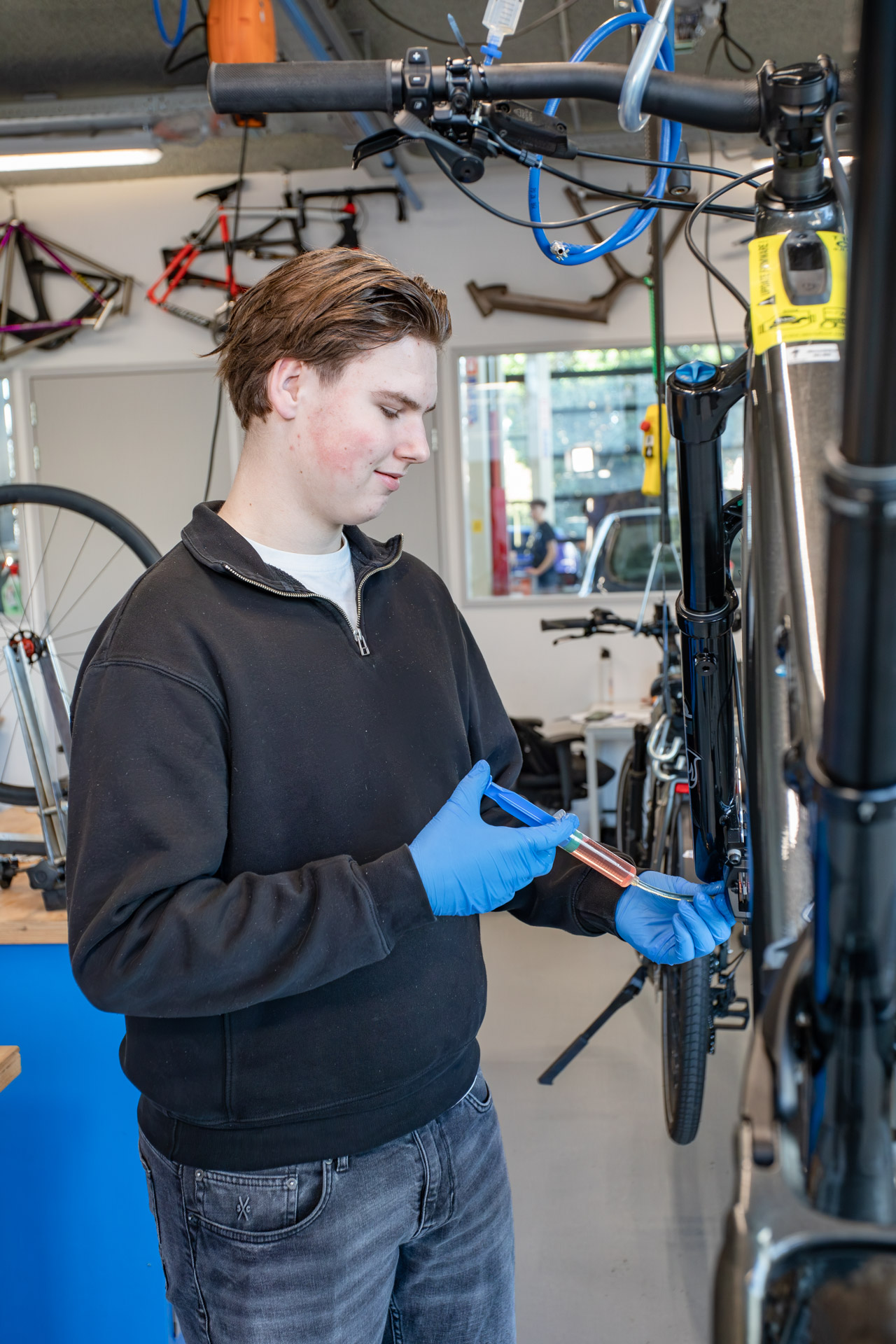 Een jongen die olie bij de fietsketting spuit.