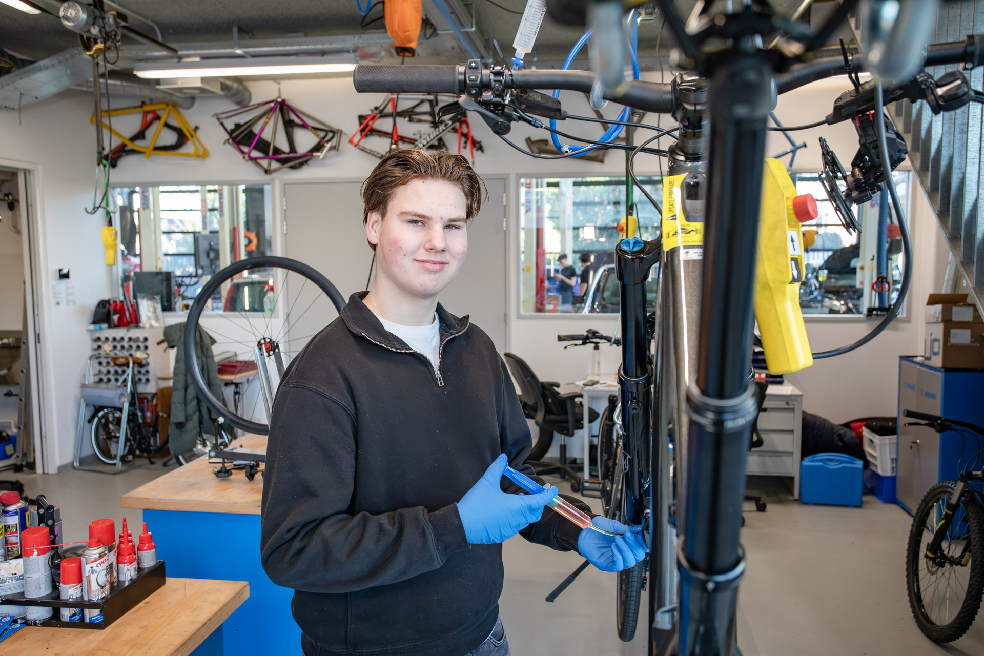 jongen kijk in de camera terwijl hij een spuit in de hand heeft en dit in de lager van de fiets spuit