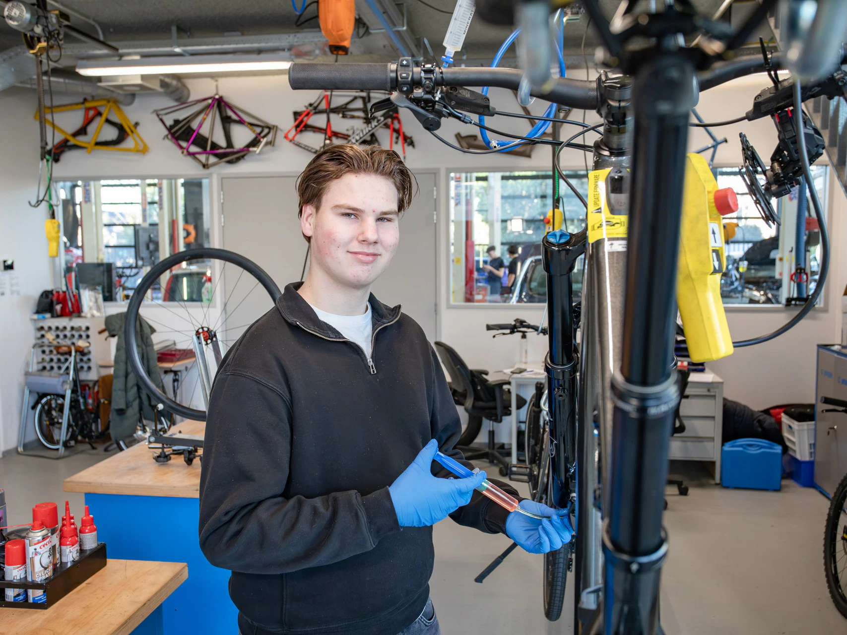 jongen kijk in de camera terwijl hij een spuit in de hand heeft en dit in de lager van de fiets spuit