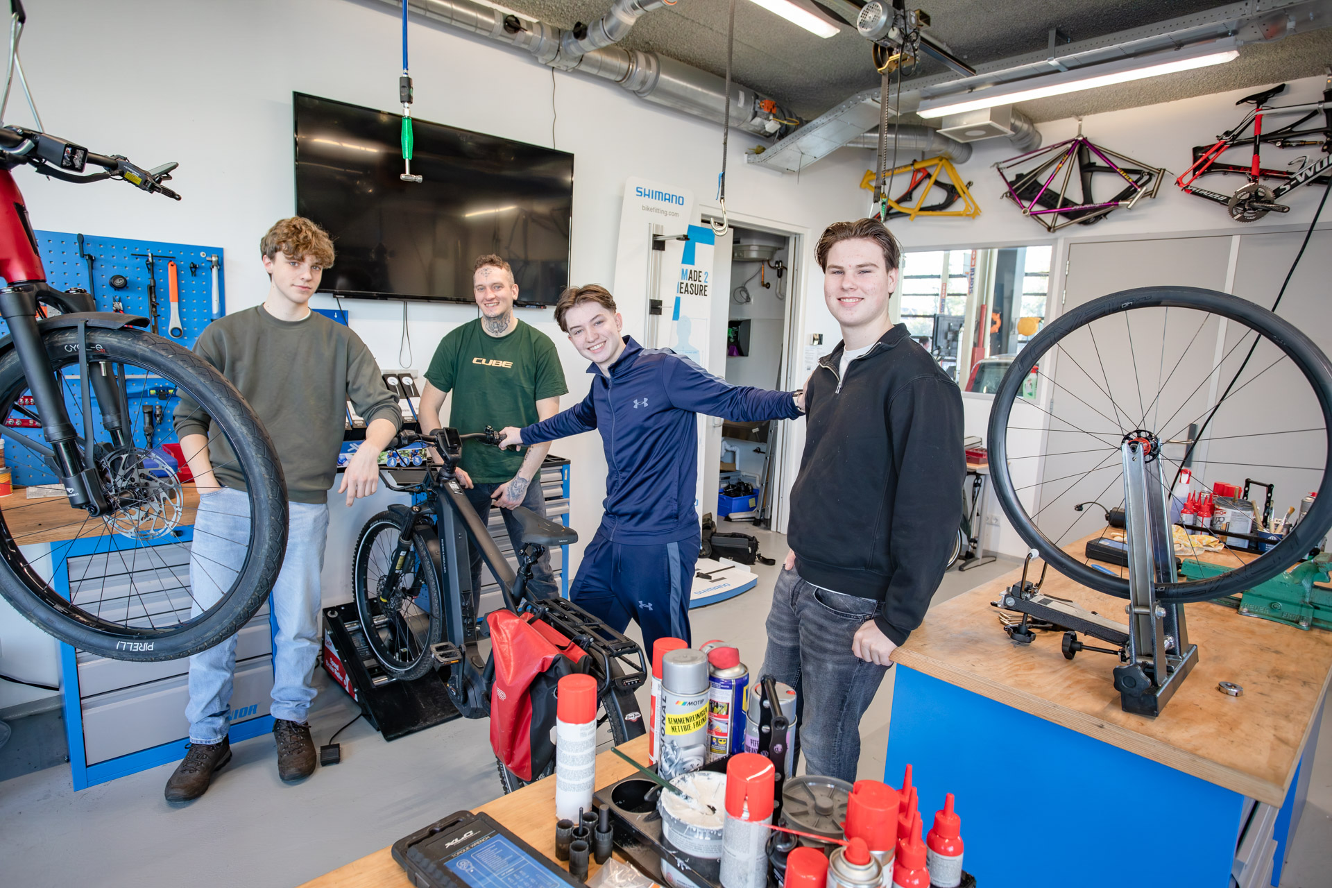 2 jongens kijken in de camera terwijl ze in een werkplaats staan met fietsen