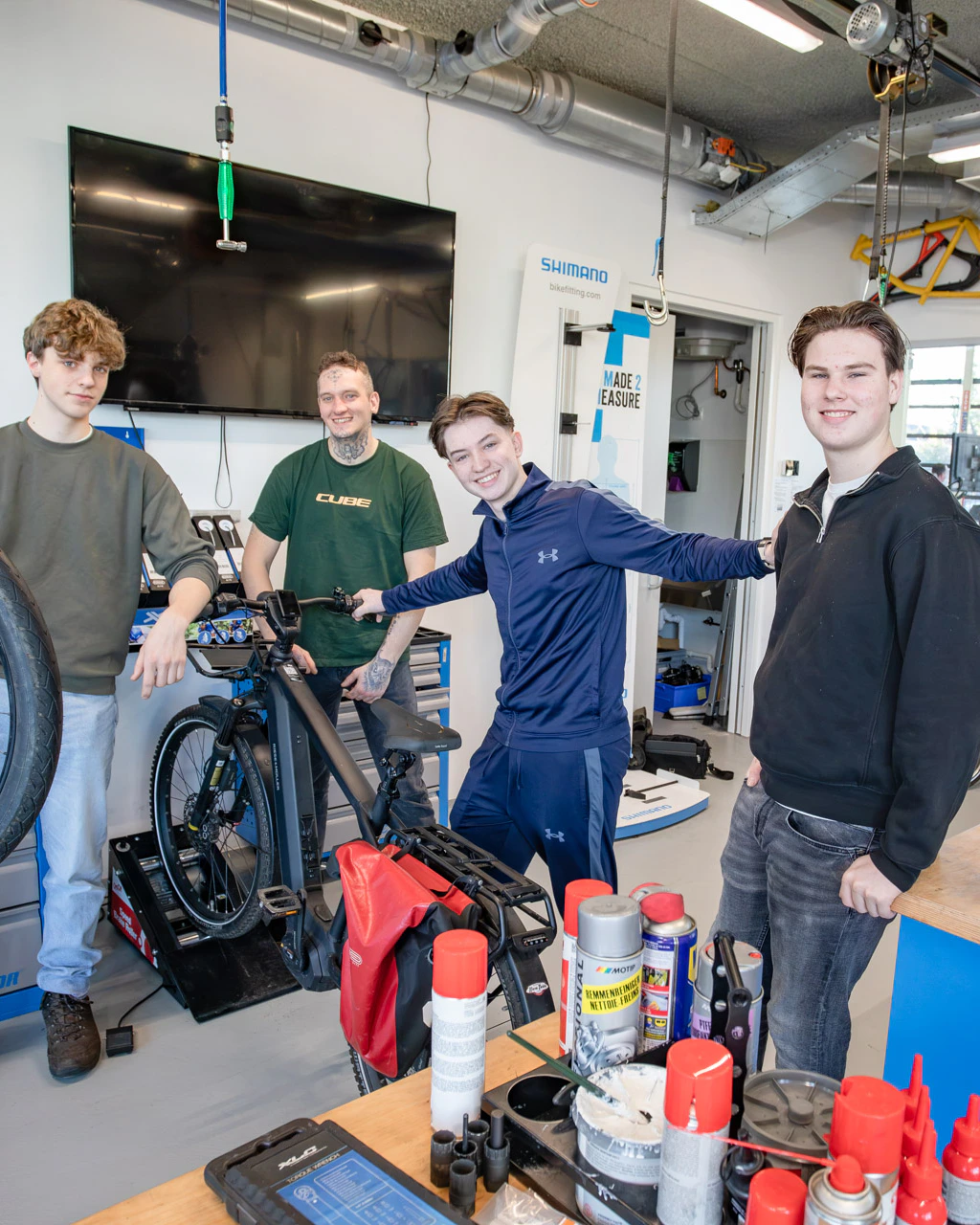 2 jongens kijken in de camera terwijl ze in een werkplaats staan met fietsen
