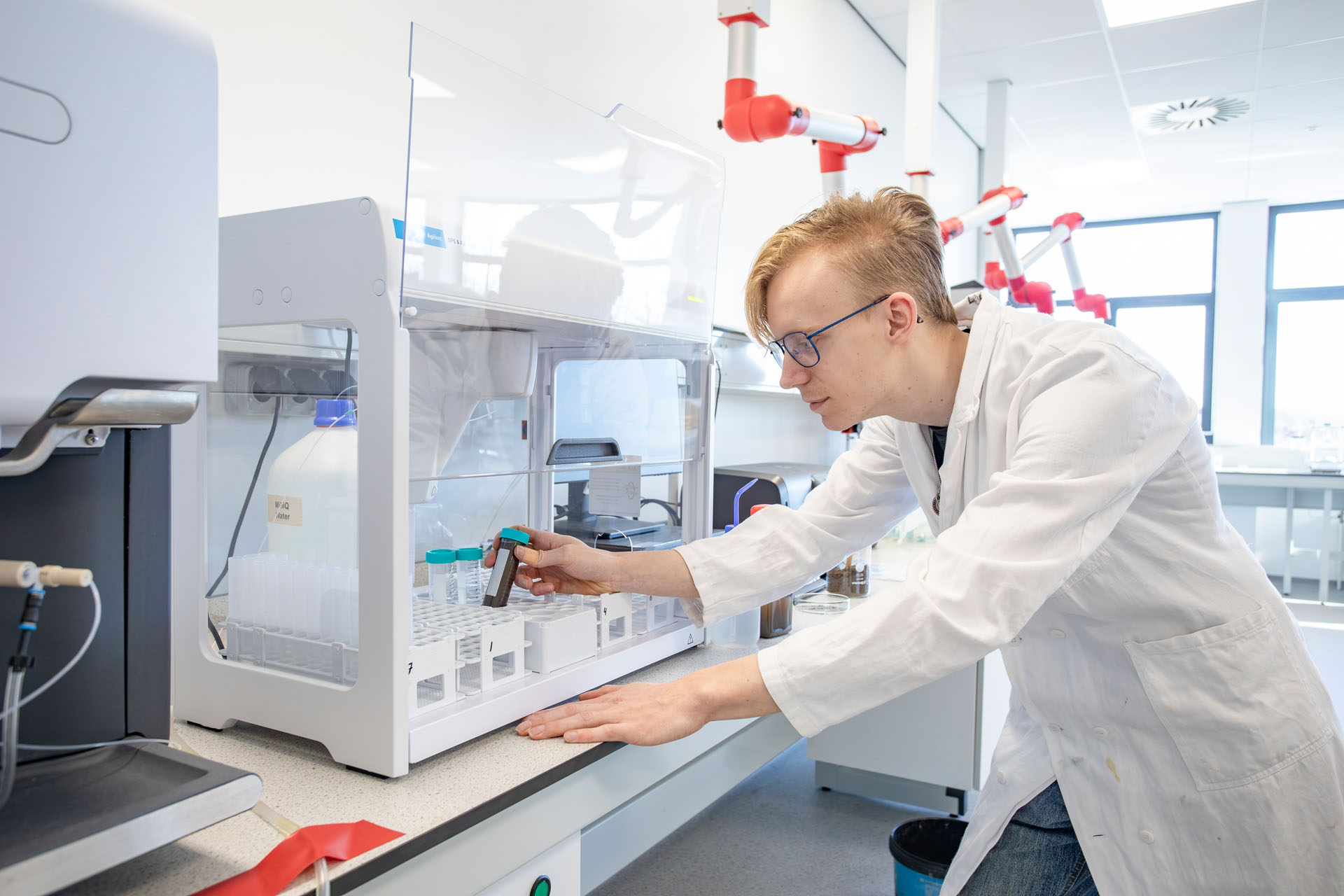 Jongen in een labaratoriumjas zit achter een microscoop