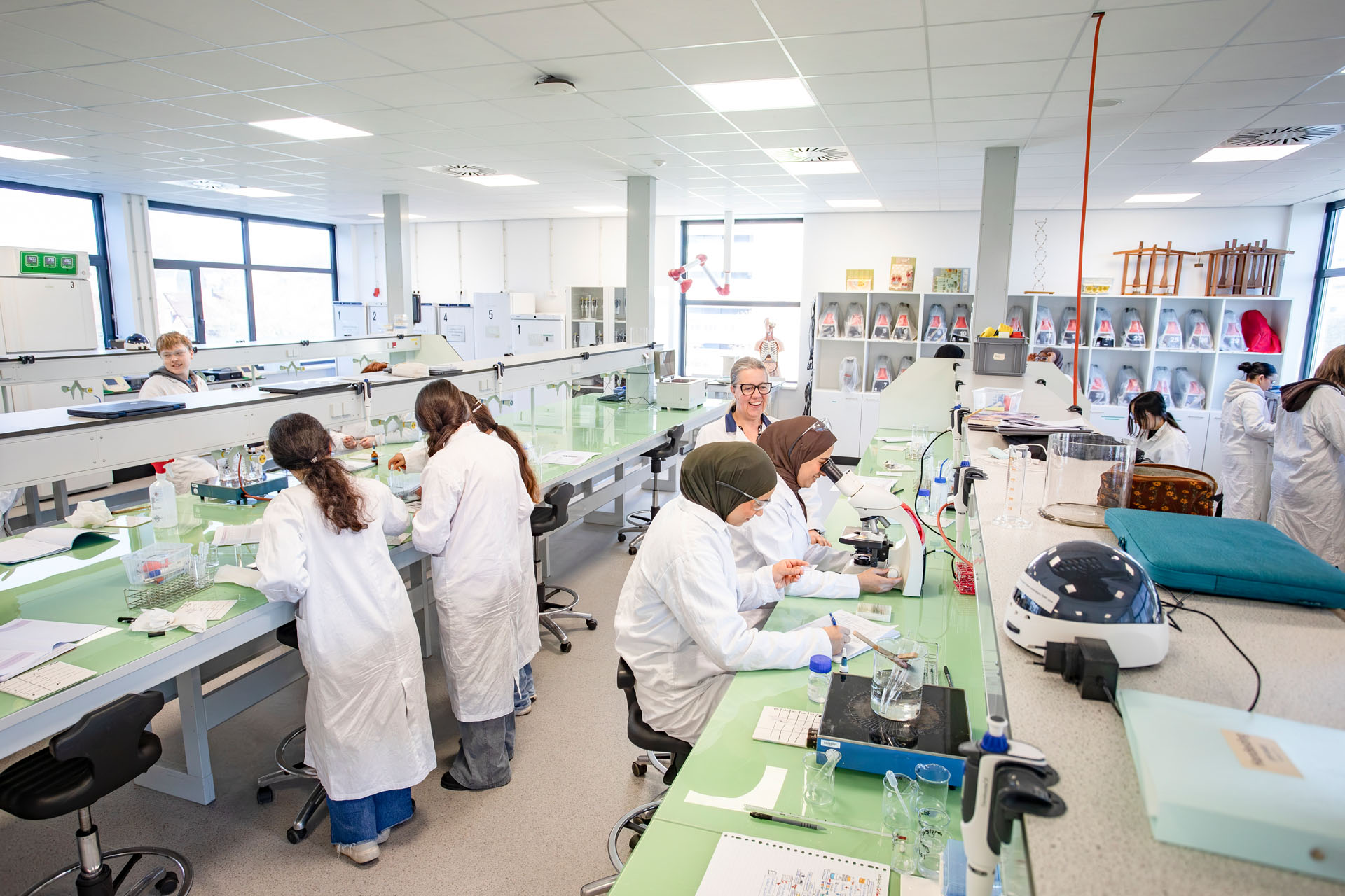 Je ziet een laboratorium waar meerdere personen aan het werk zijn