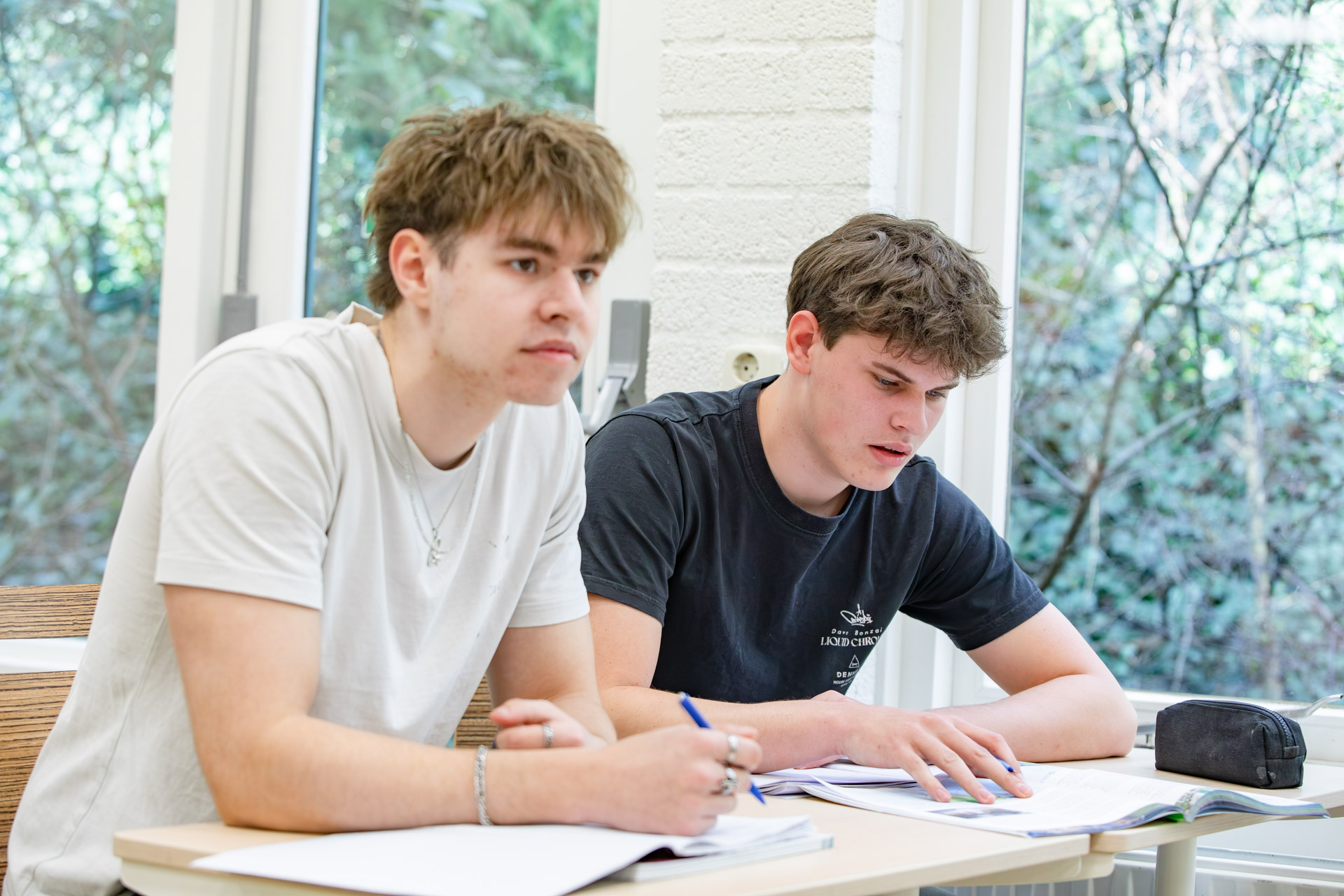 Twee jongens in een klaslokaal die de instructie van de docent volgen.