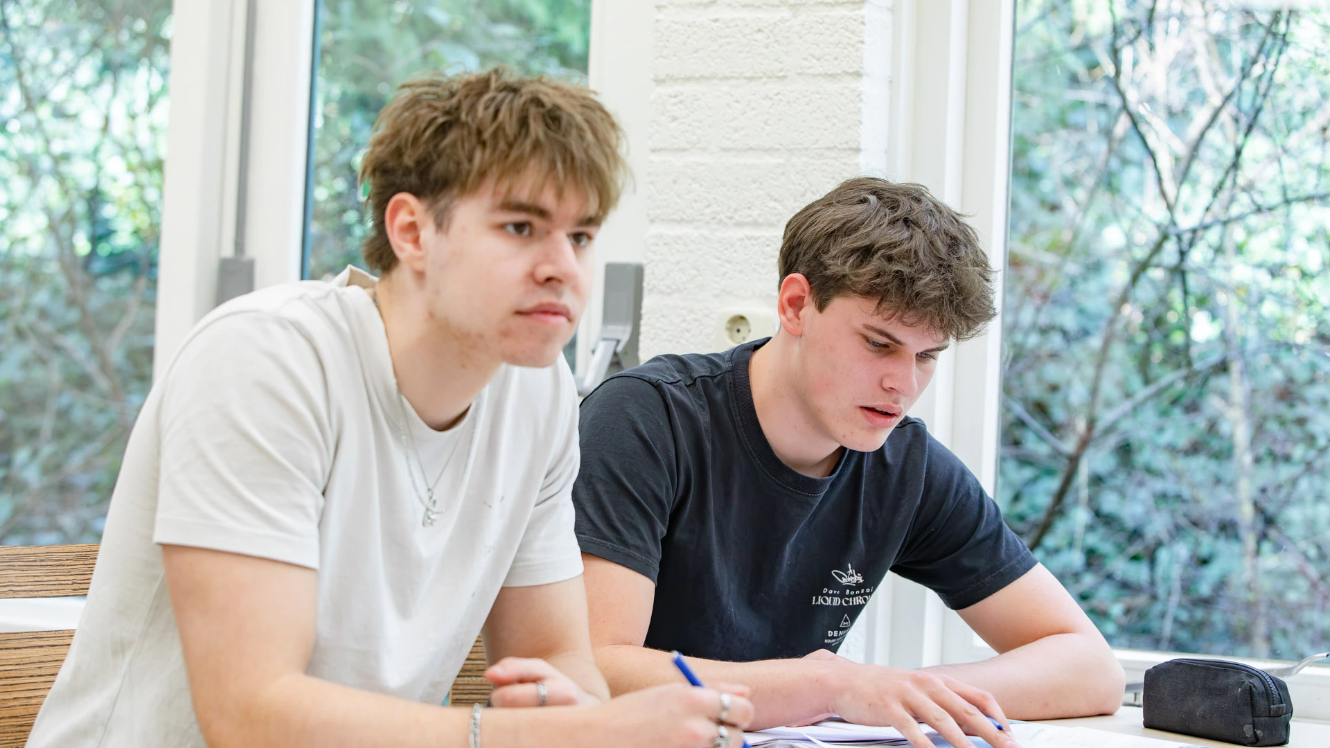 Twee jongens in een klaslokaal die de instructie van de docent volgen.