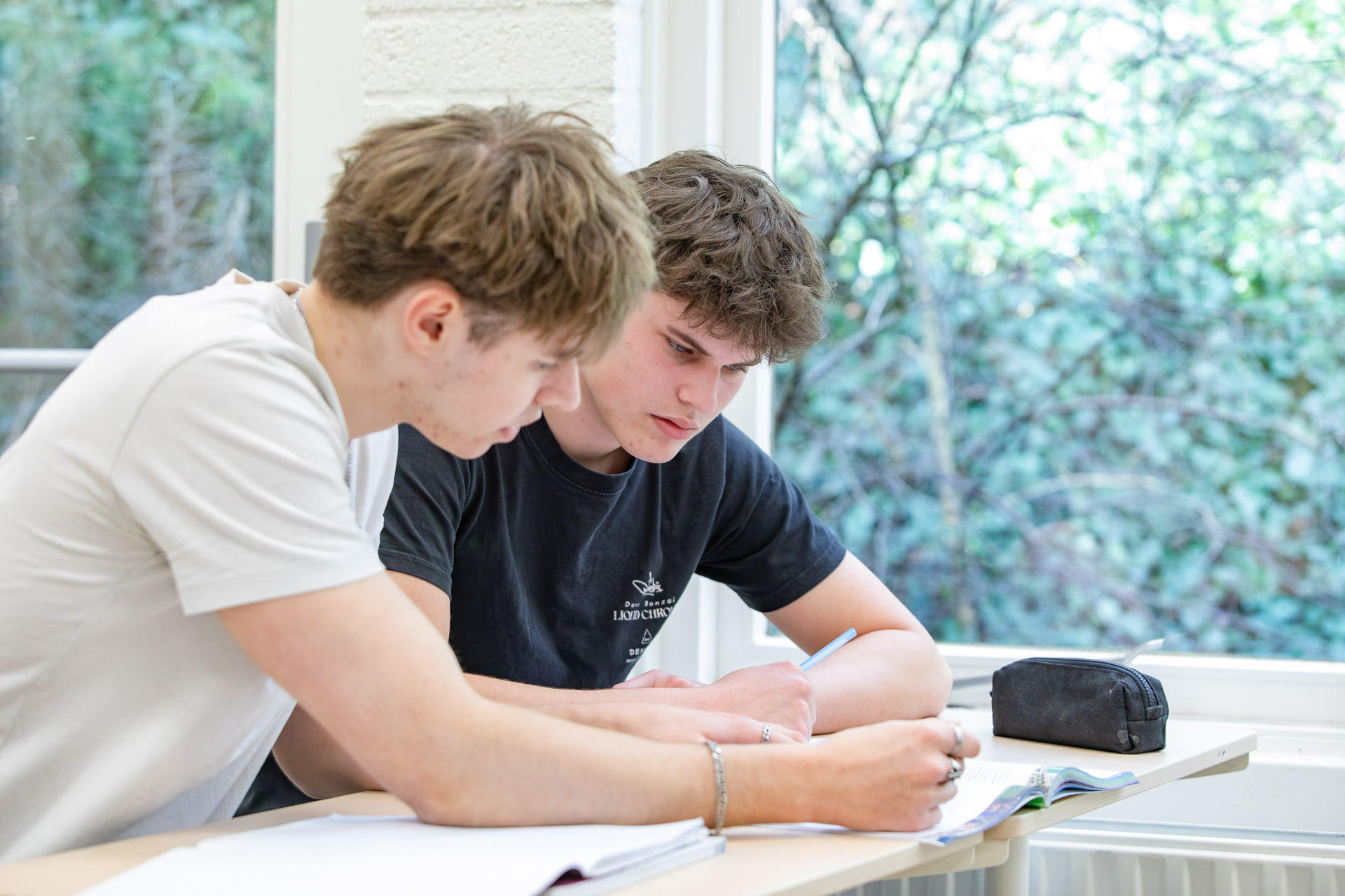 Twee jongen in een klaslokaal die samenwerken in een schrift.
