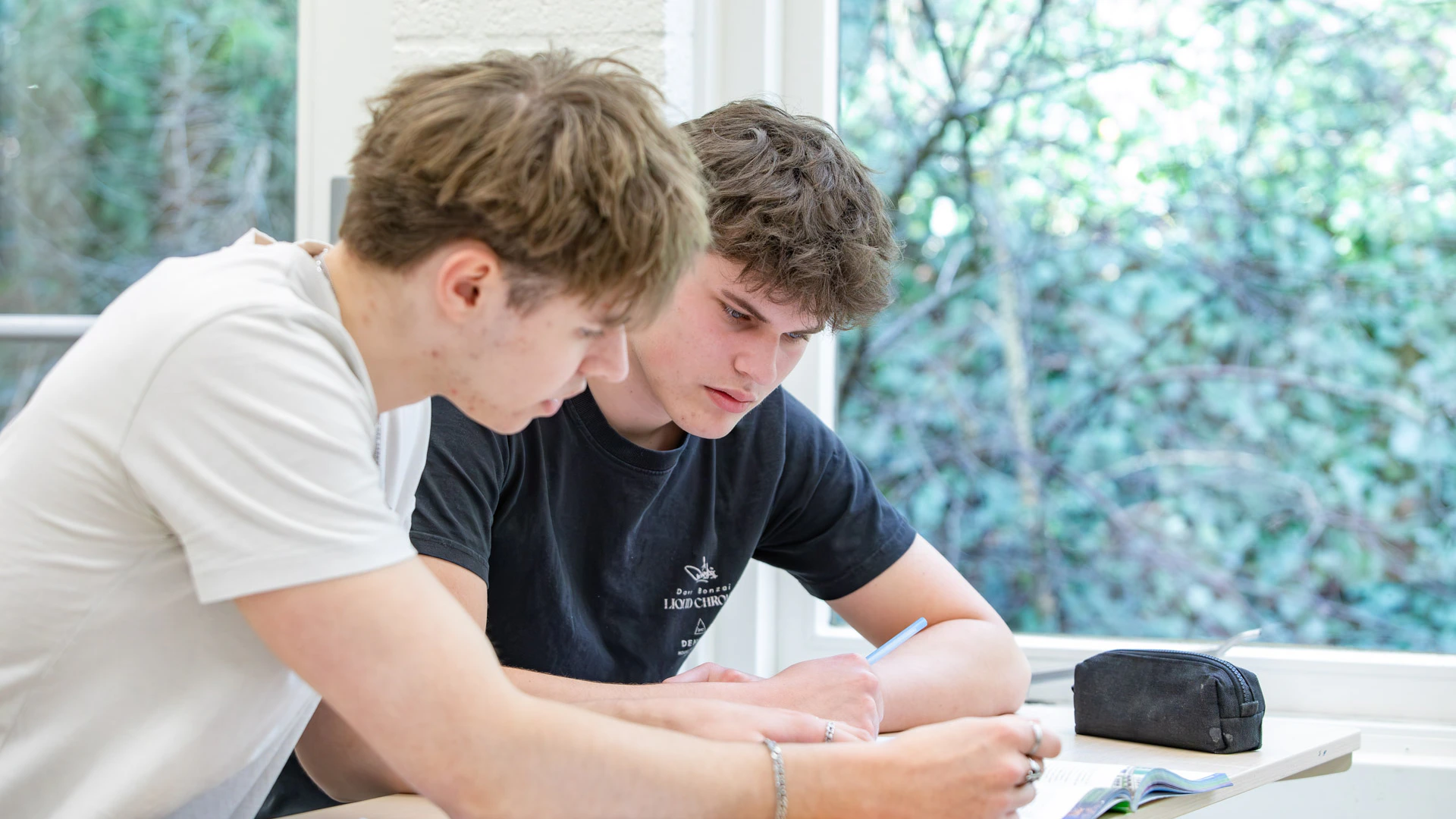 Twee jongen in een klaslokaal die samenwerken in een schrift.