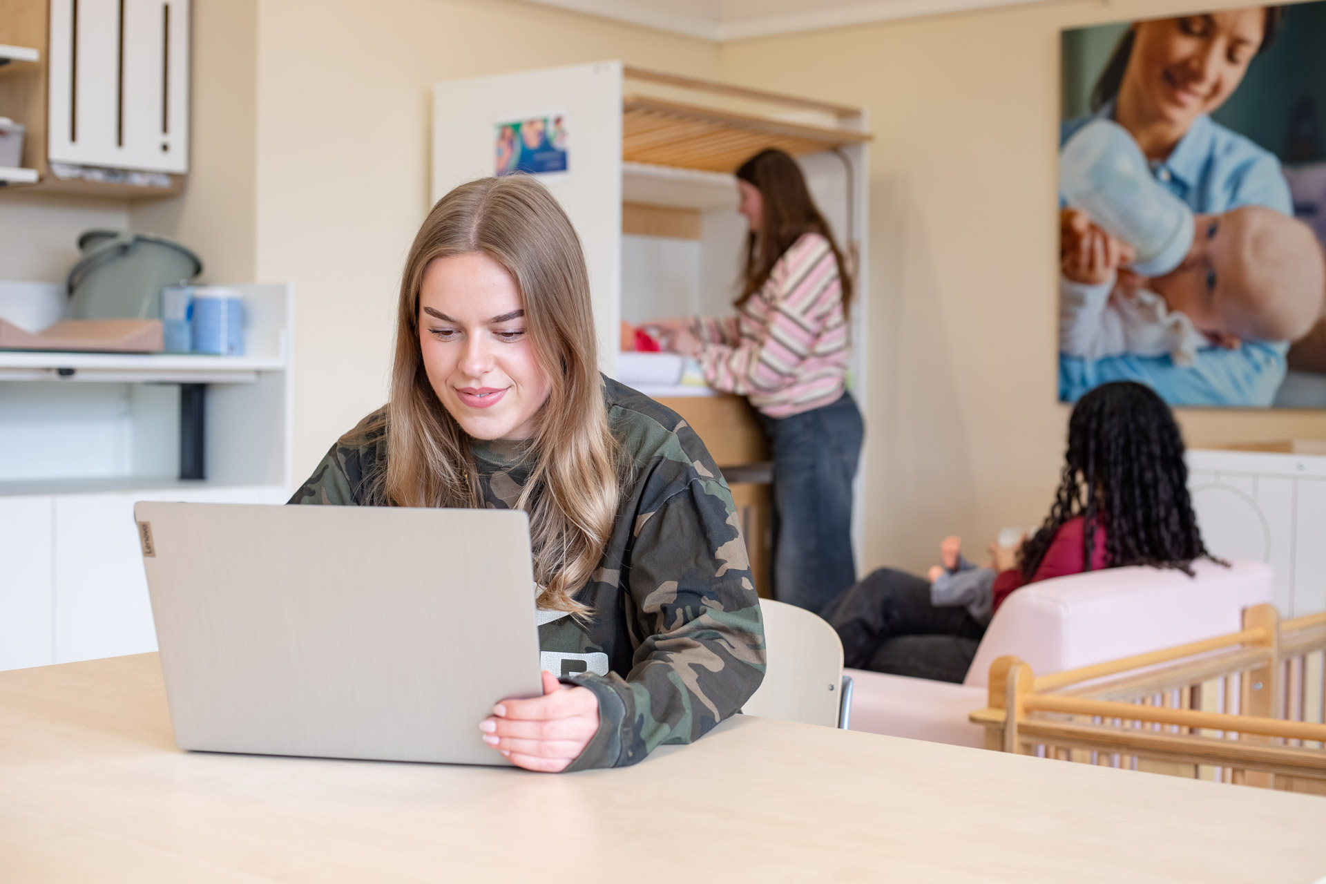 Meisje zit in een klaslokaal en werkt achter haar laptop.