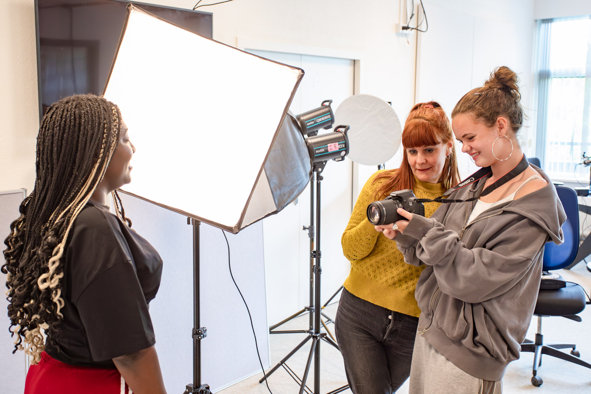 Een docent legt een fotocamera uit aan een meisje.