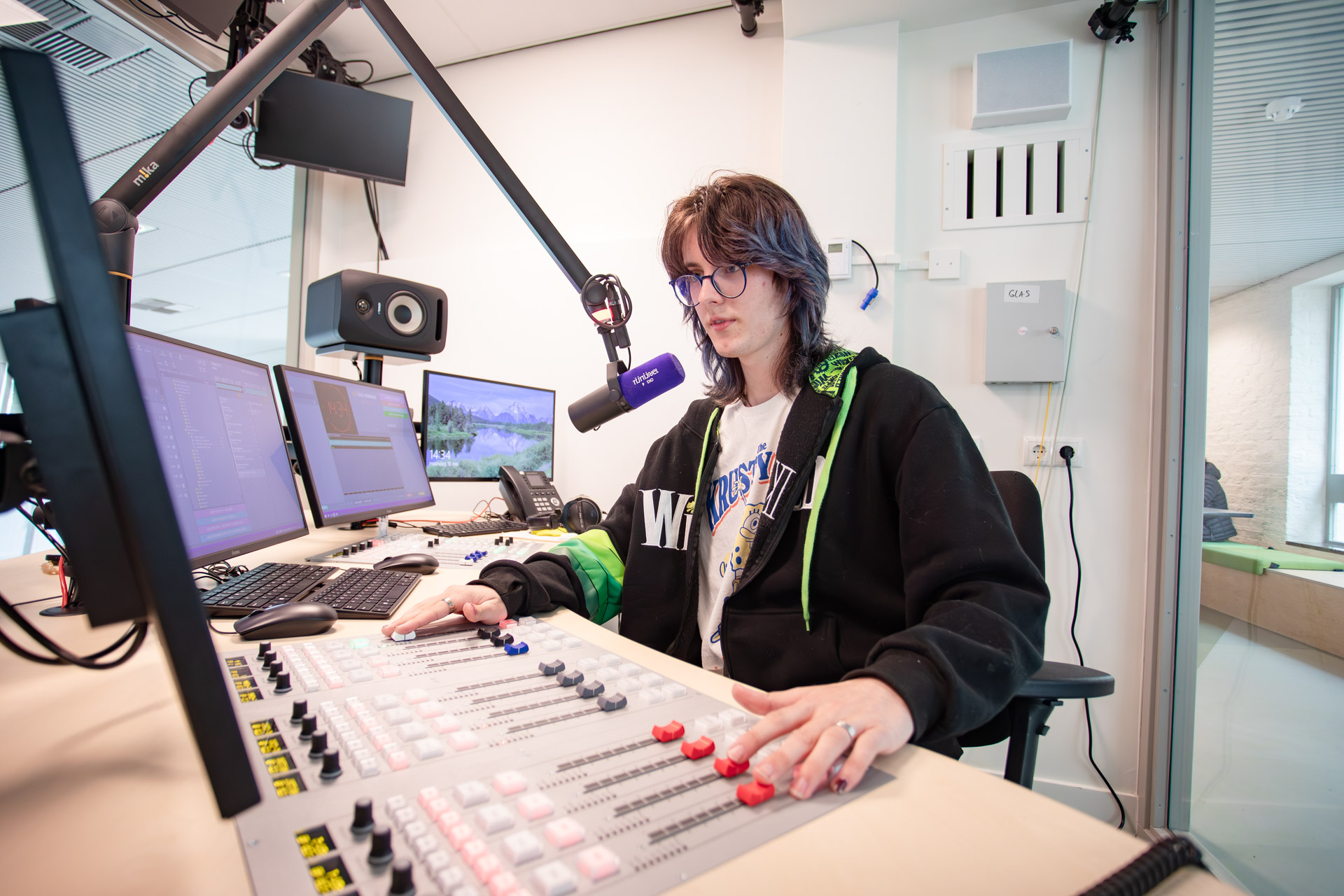 Een jongen maakt radio in een radiostudio.
