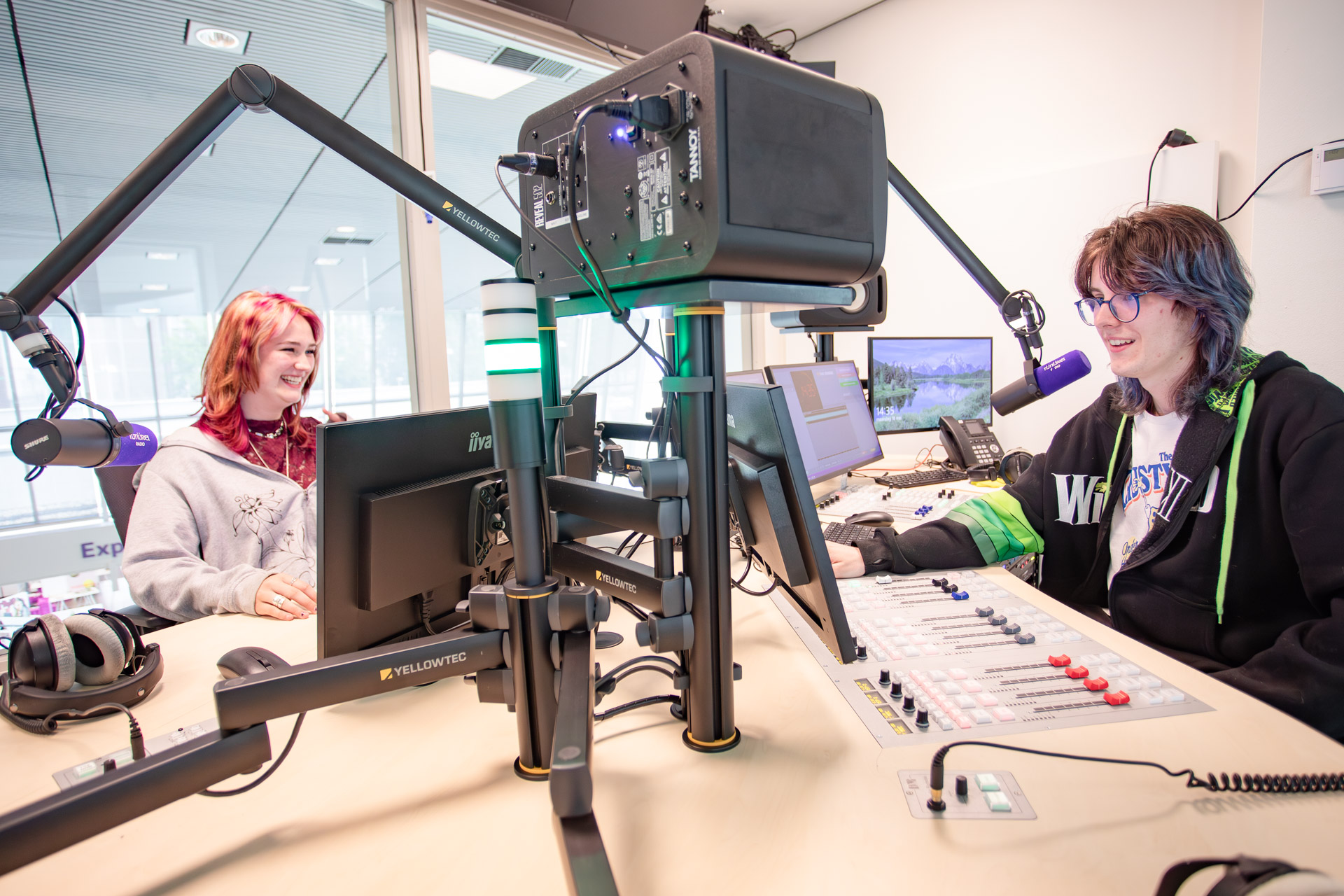 Een jongen en een meisje maken radio in een radiostudio.