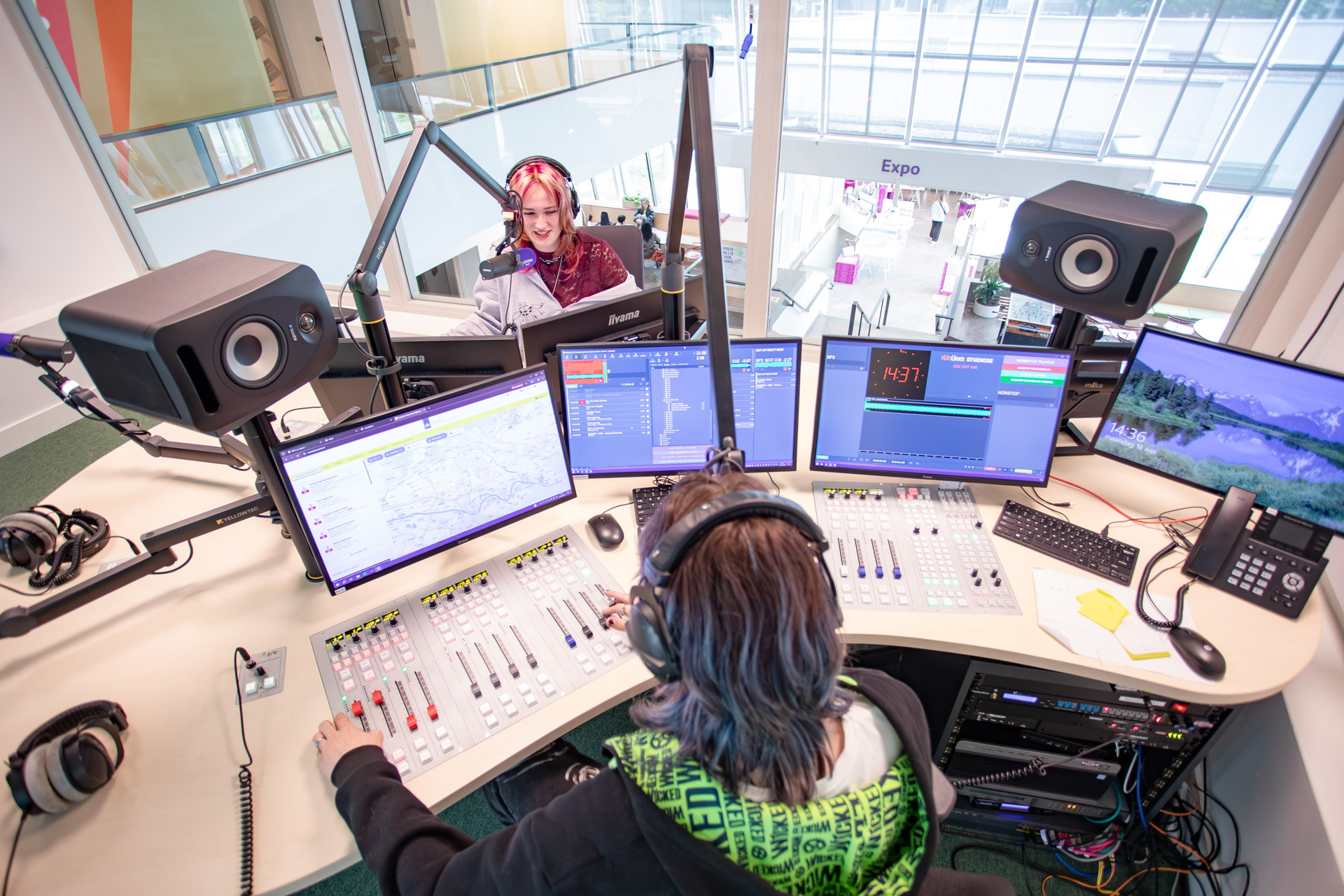 Een jongen en een meisje maken radio in een radiostudio.