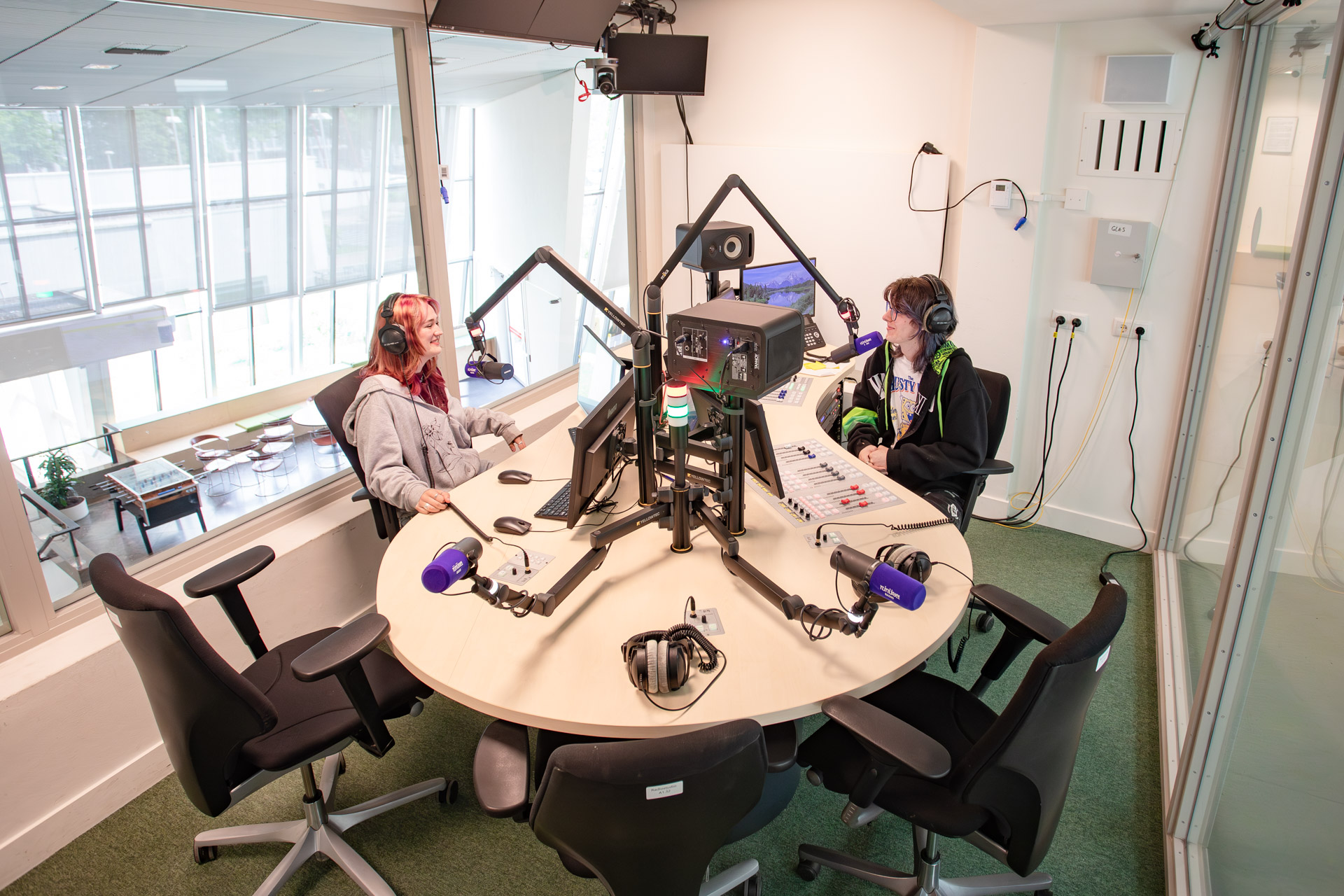 Een jongen en een meisje maken radio in een radiostudio.