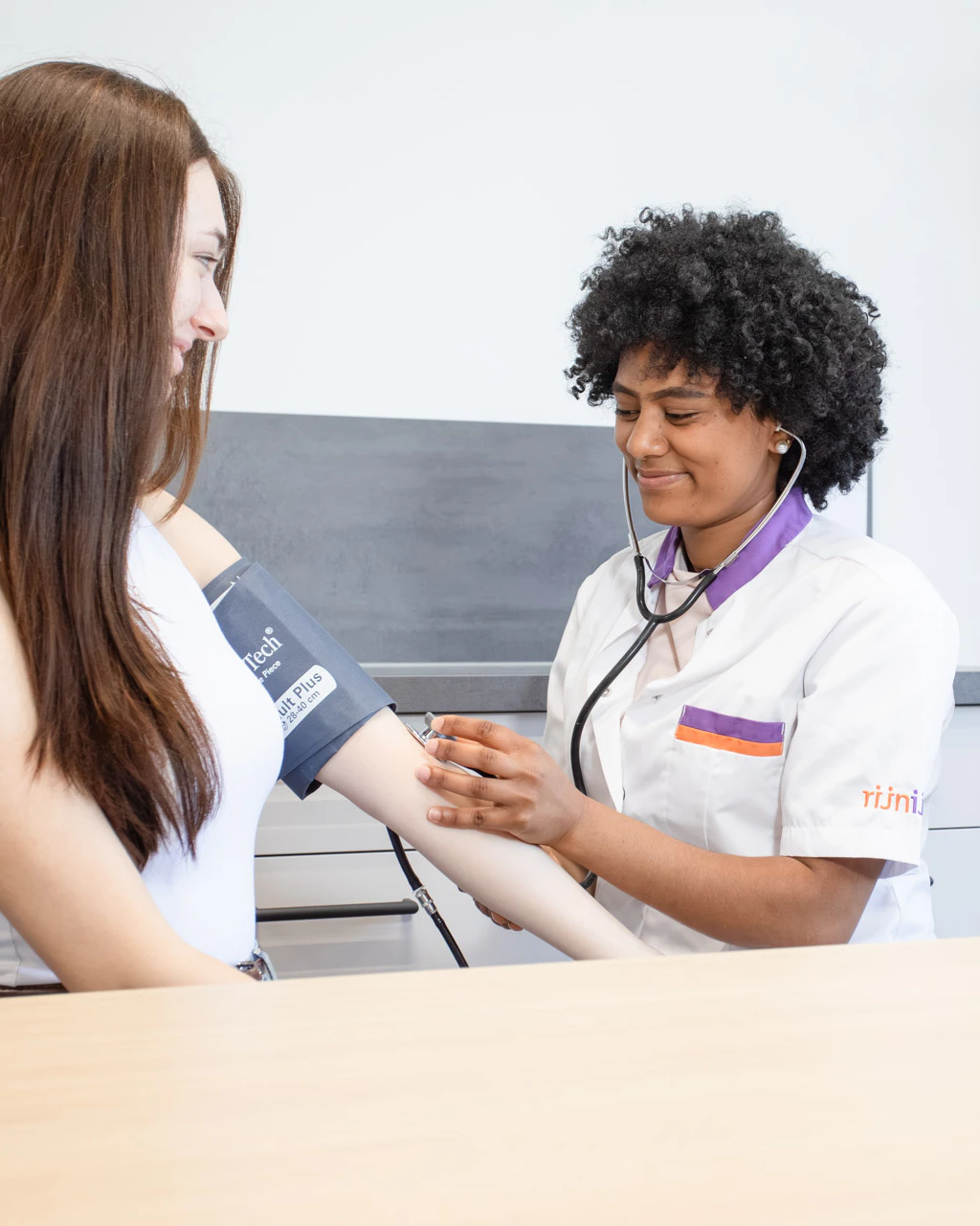 Een meisje in dokterskleding meet de bloeddruk van een patiënt op.