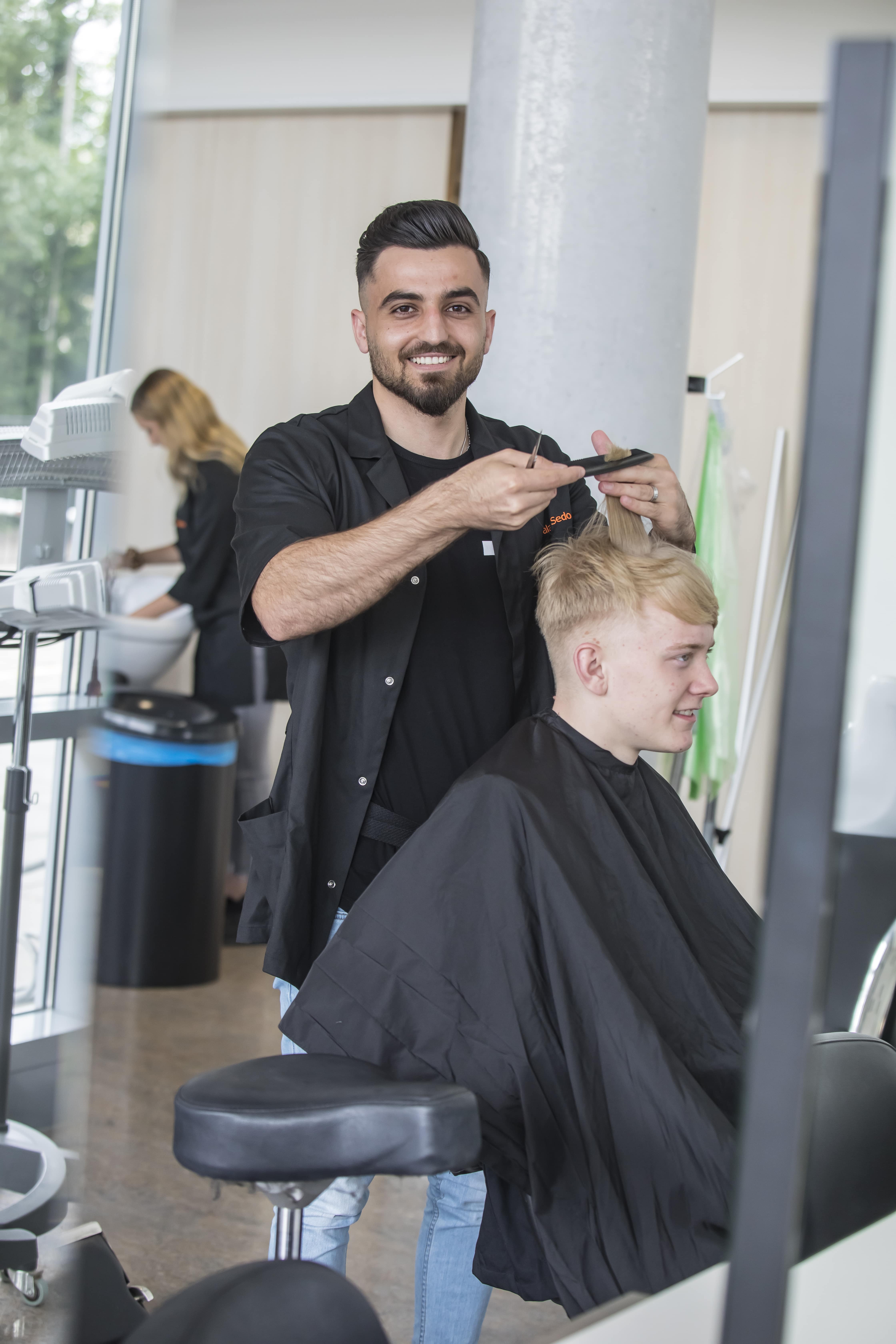 Student knipt het haar van een andere student