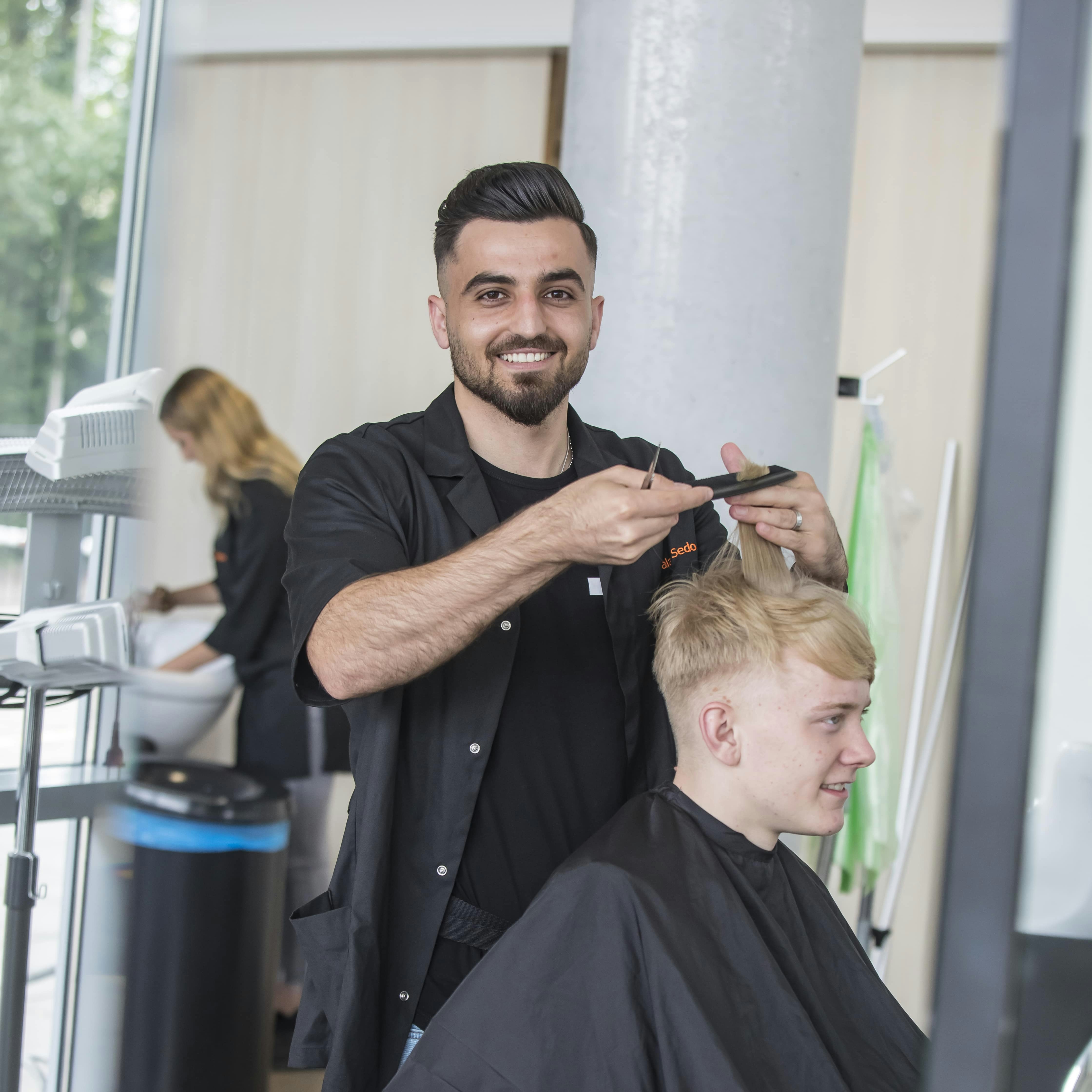Student knipt het haar van een andere student