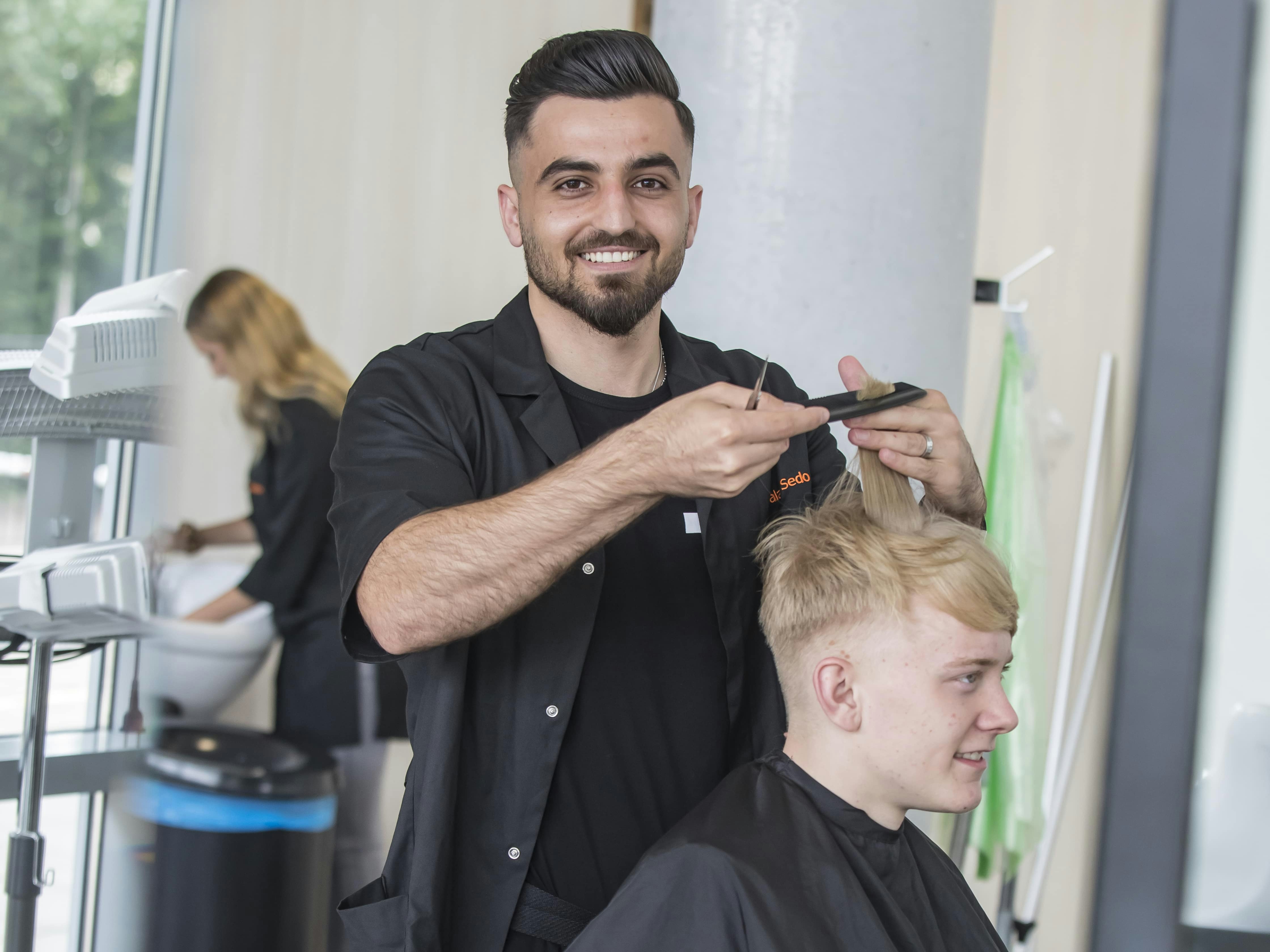 Student knipt het haar van een andere student