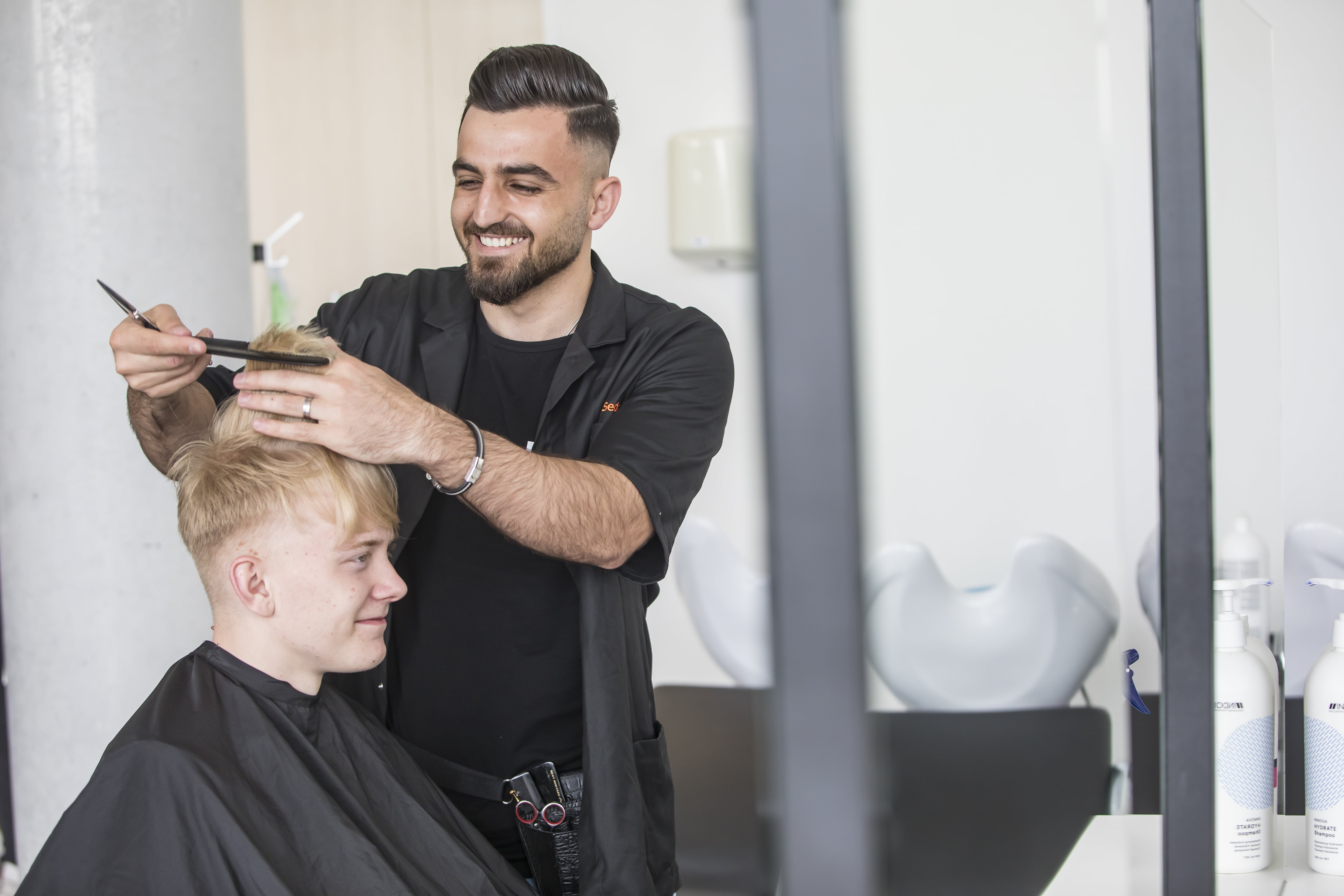 Student lacht met kam in zijn hand