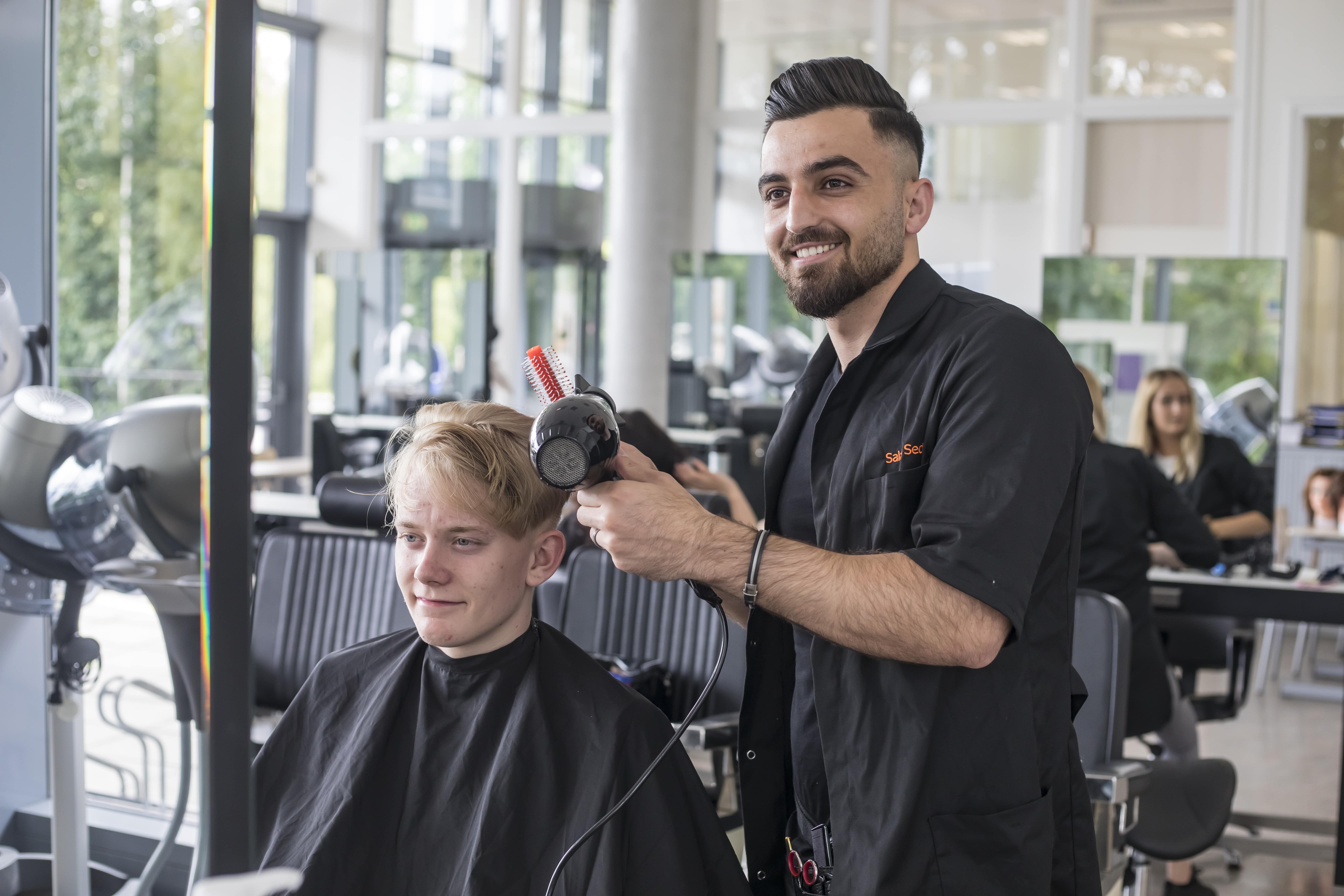 Student lacht naar de spiegel met föhn