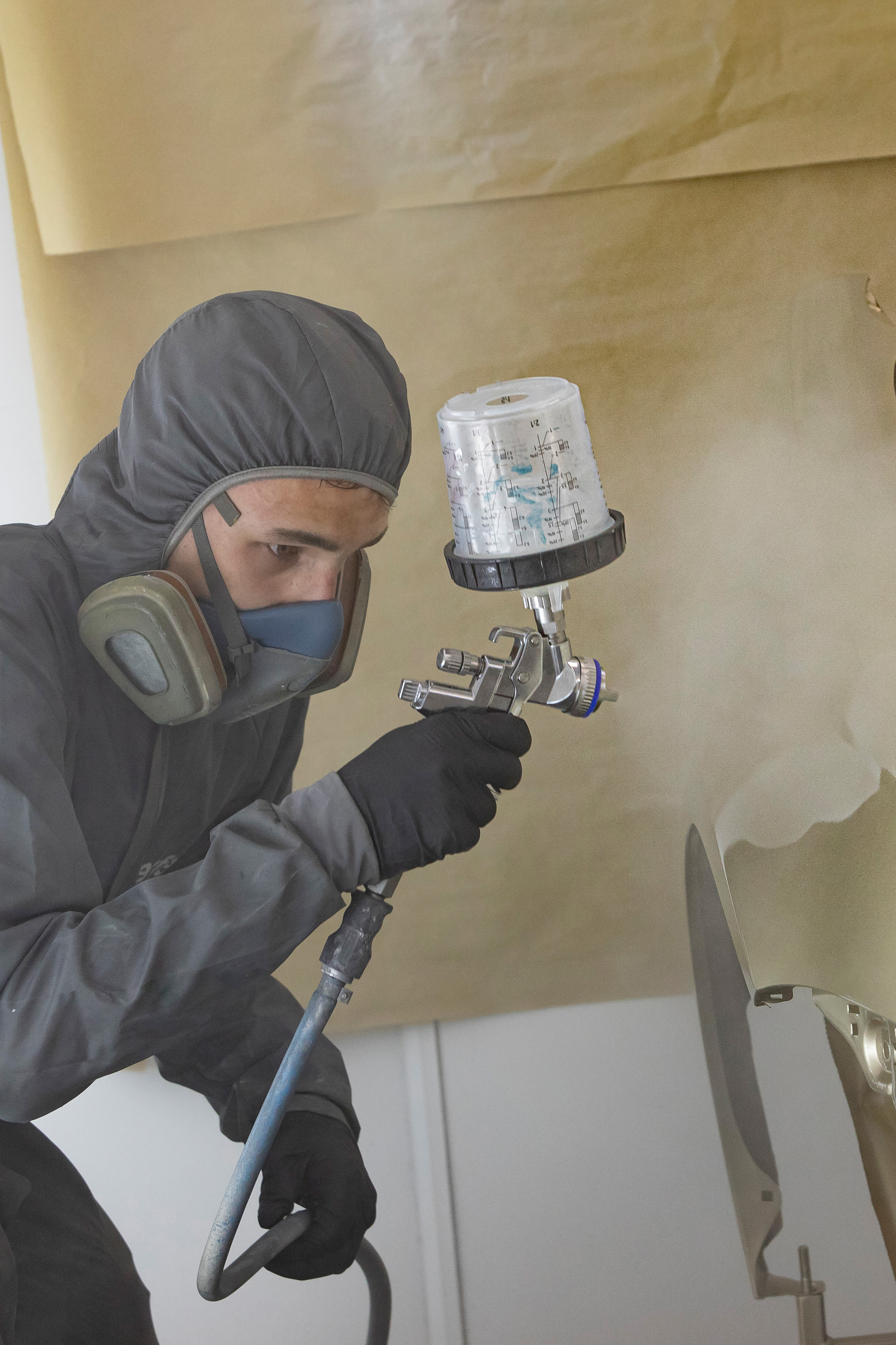 Student in werkkleding is een auto aan het spuiten