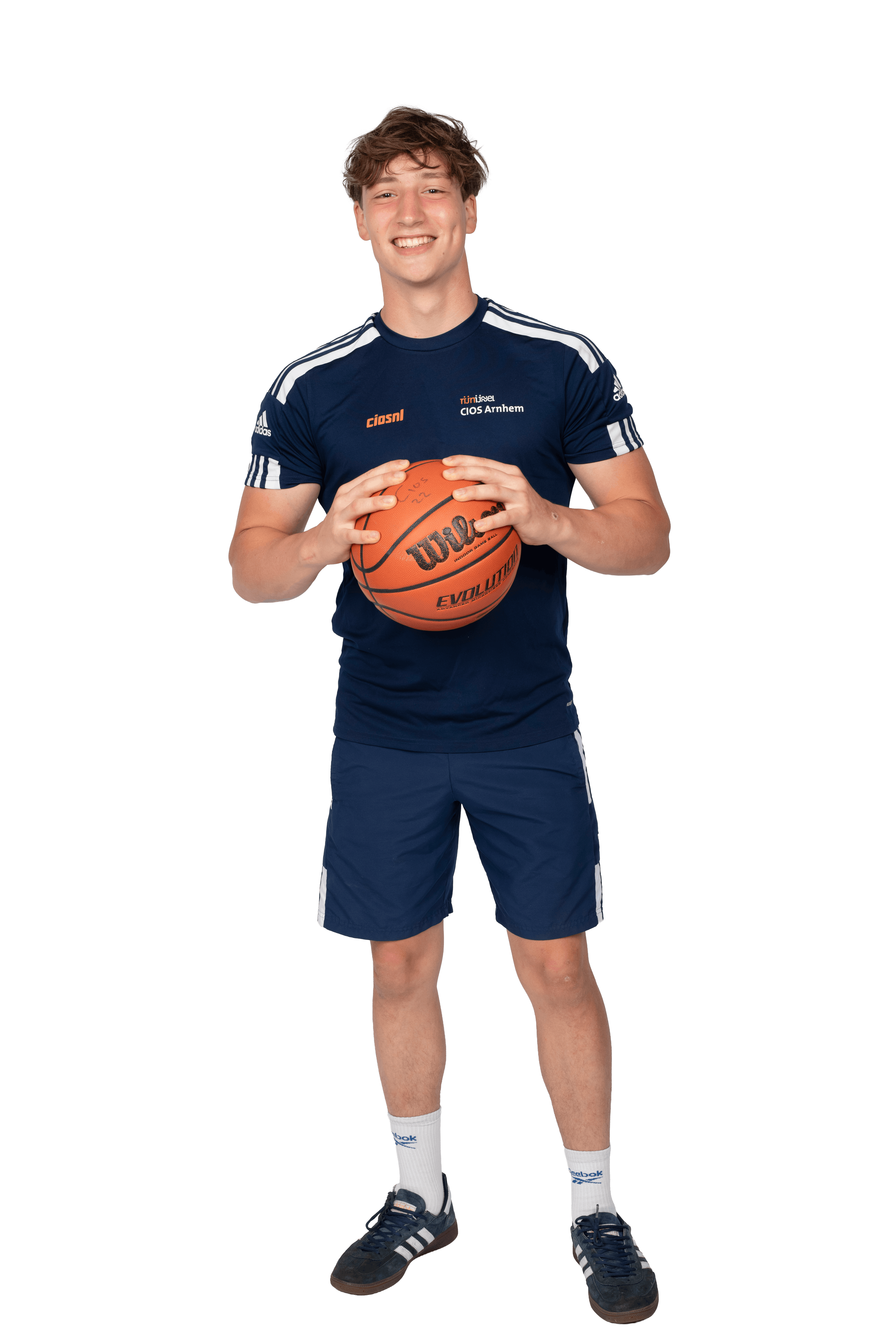 Een jongen in sportieve kleding heeft een basketbal in zijn handen en poseert voor de camera.