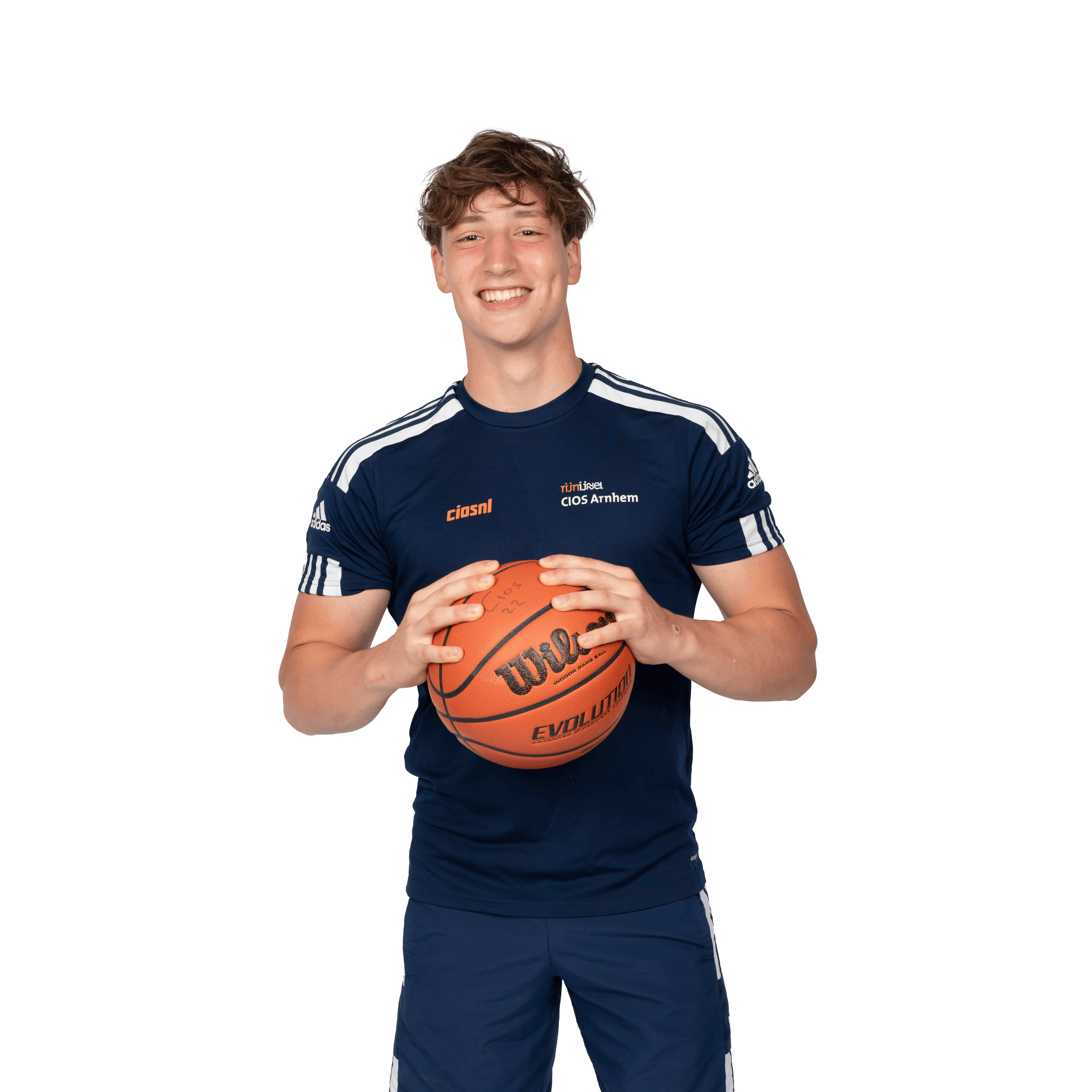 Een jongen in sportieve kleding heeft een basketbal in zijn handen en poseert voor de camera.