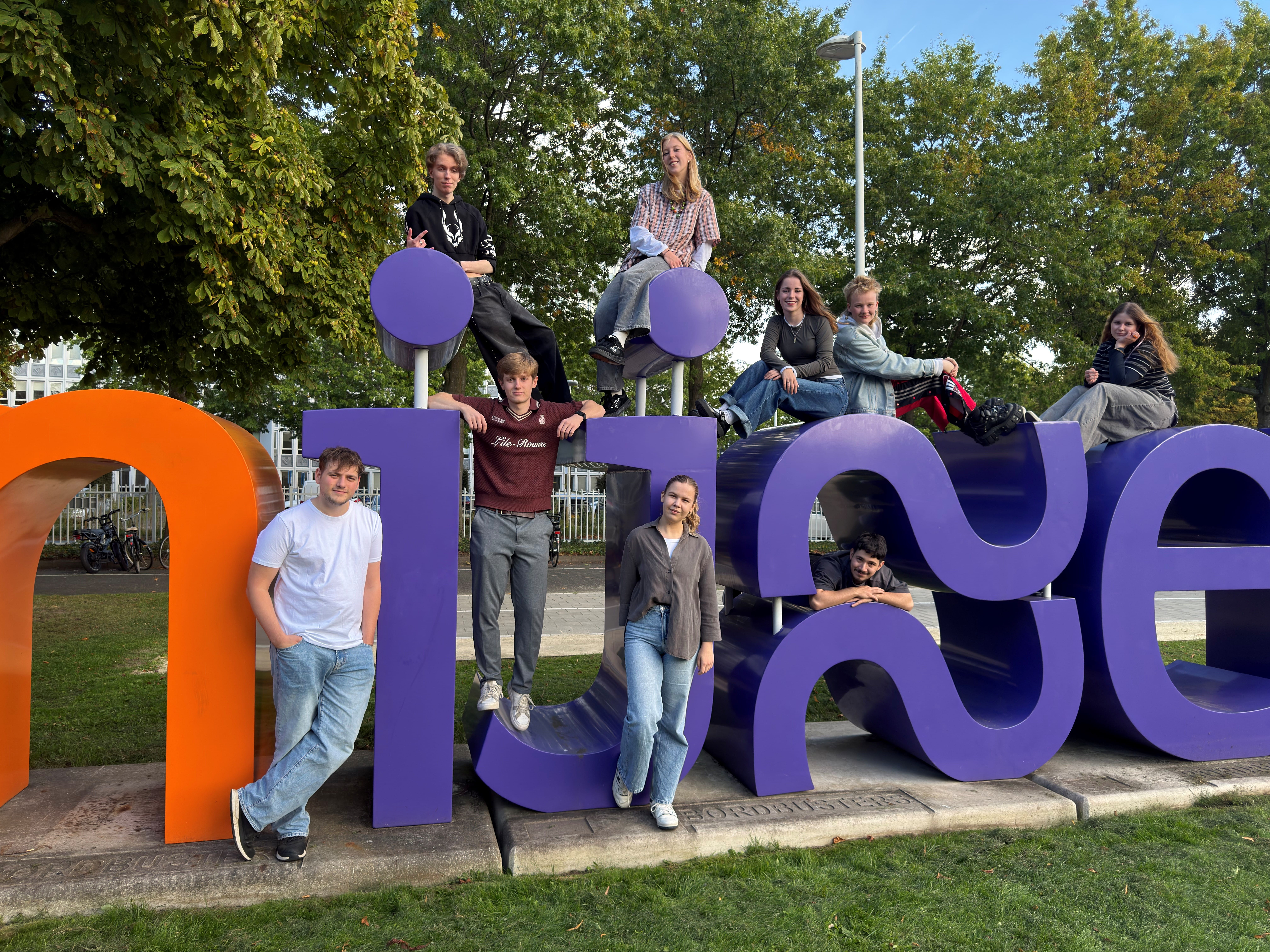 Groep studenten poseert voor het grote logo van Rijn IJssel