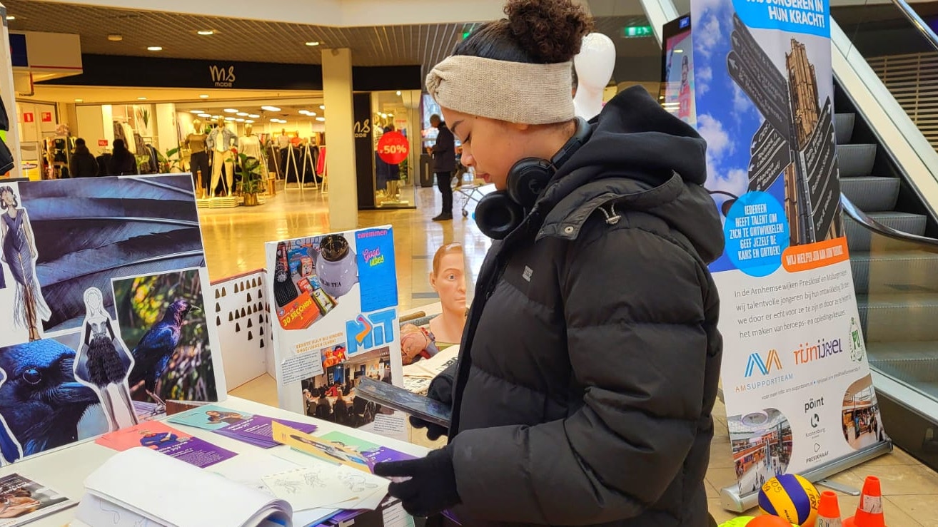 Jongere kijkt naar flyers op studiemarkt.