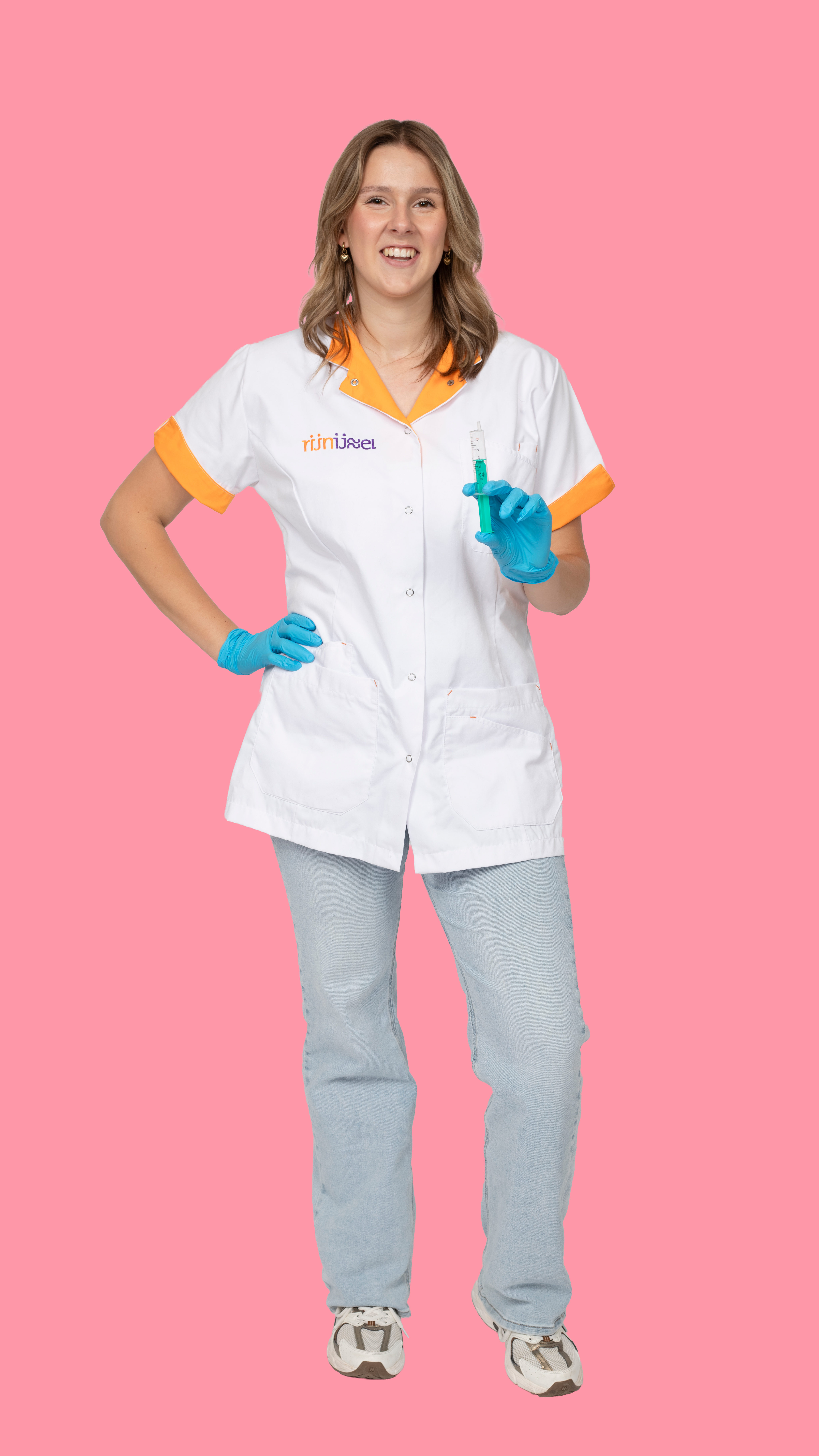 Meisje in dokterskleding en handschoenen poseert voor de camera terwijl ze een spuit vasthoud.