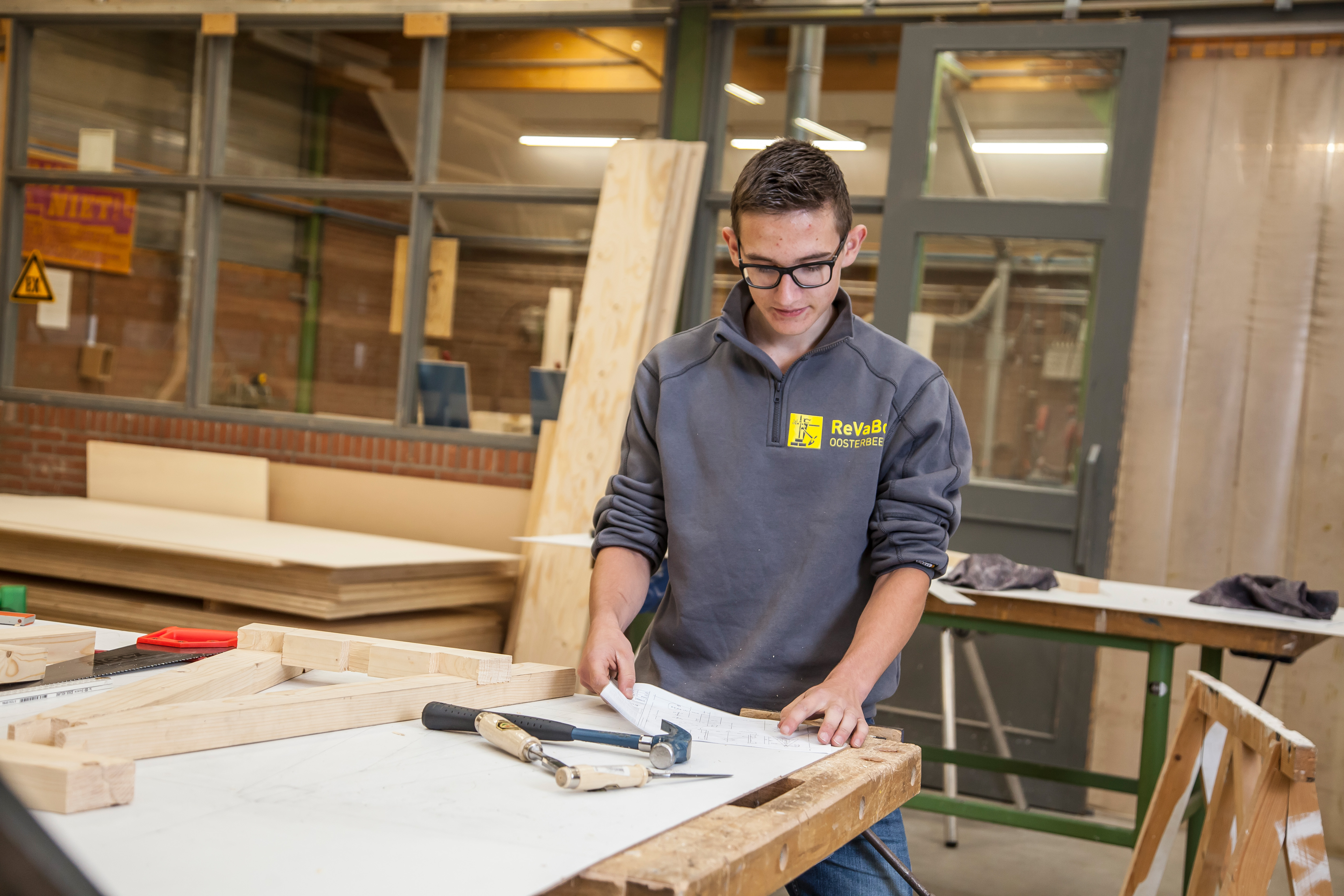 Jongen aan werktafel bezig met bouwtekeningen