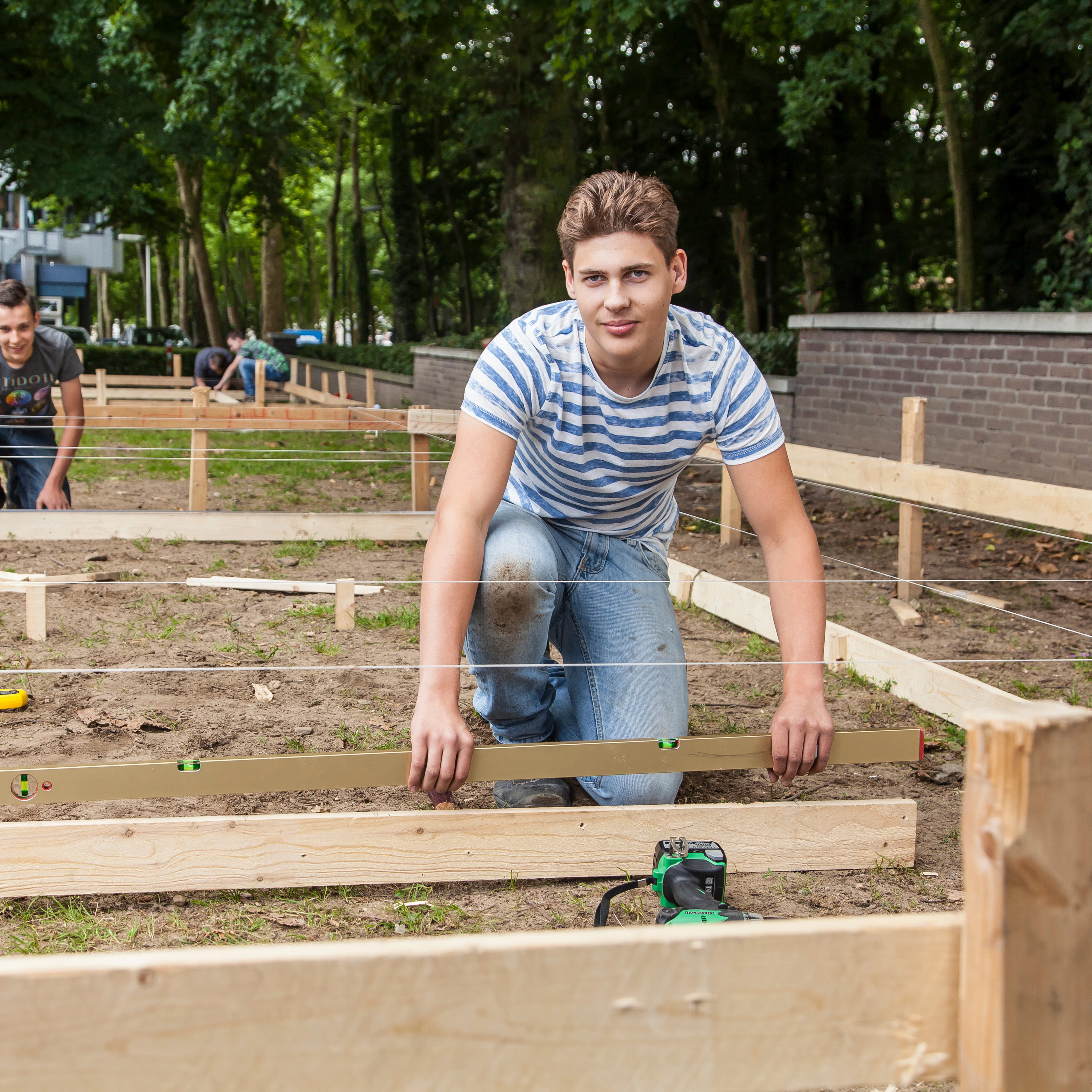 Student staat buiten en houdt houten plank vast