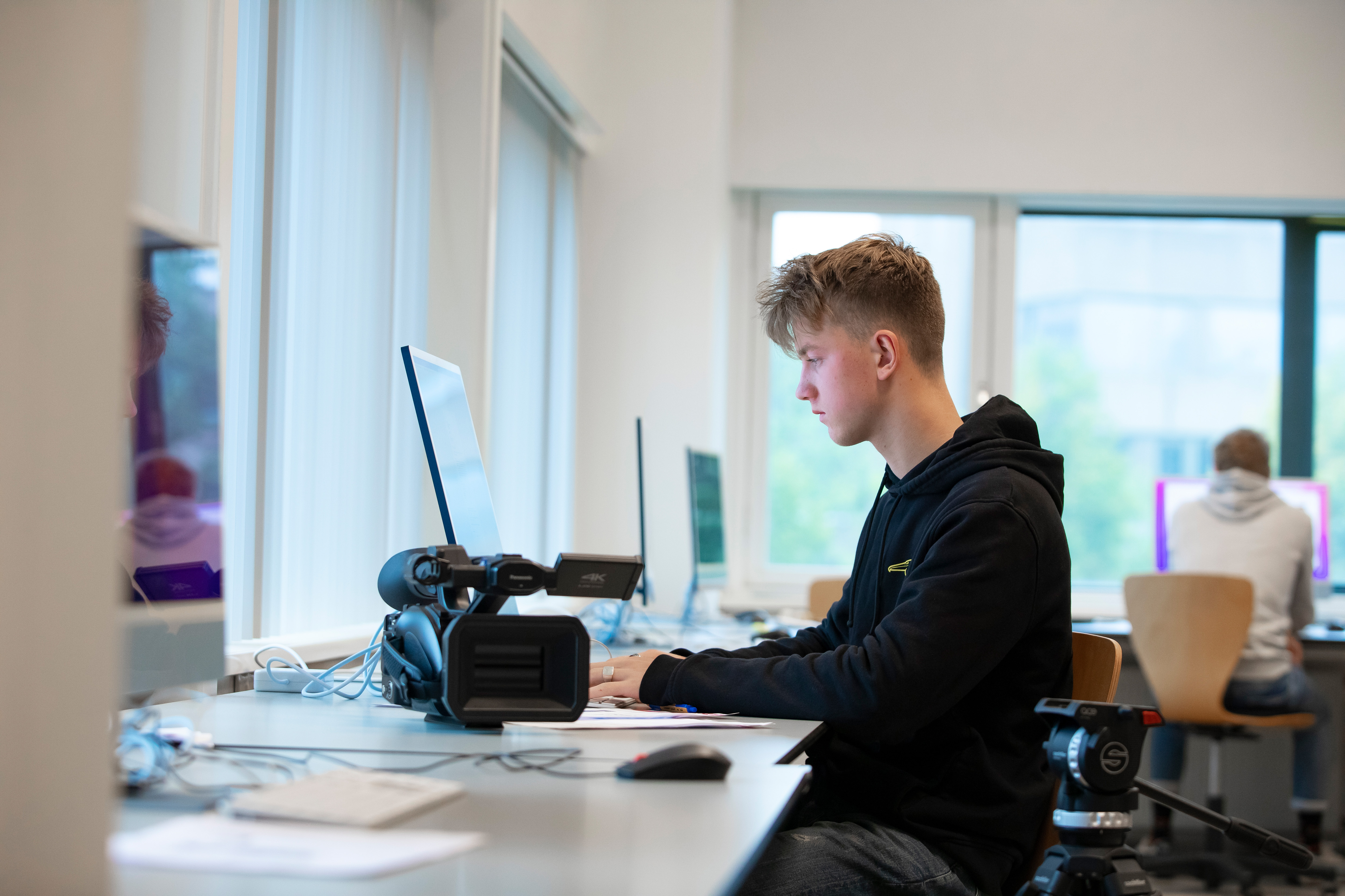 Student achter laptop met een camera op de tafel